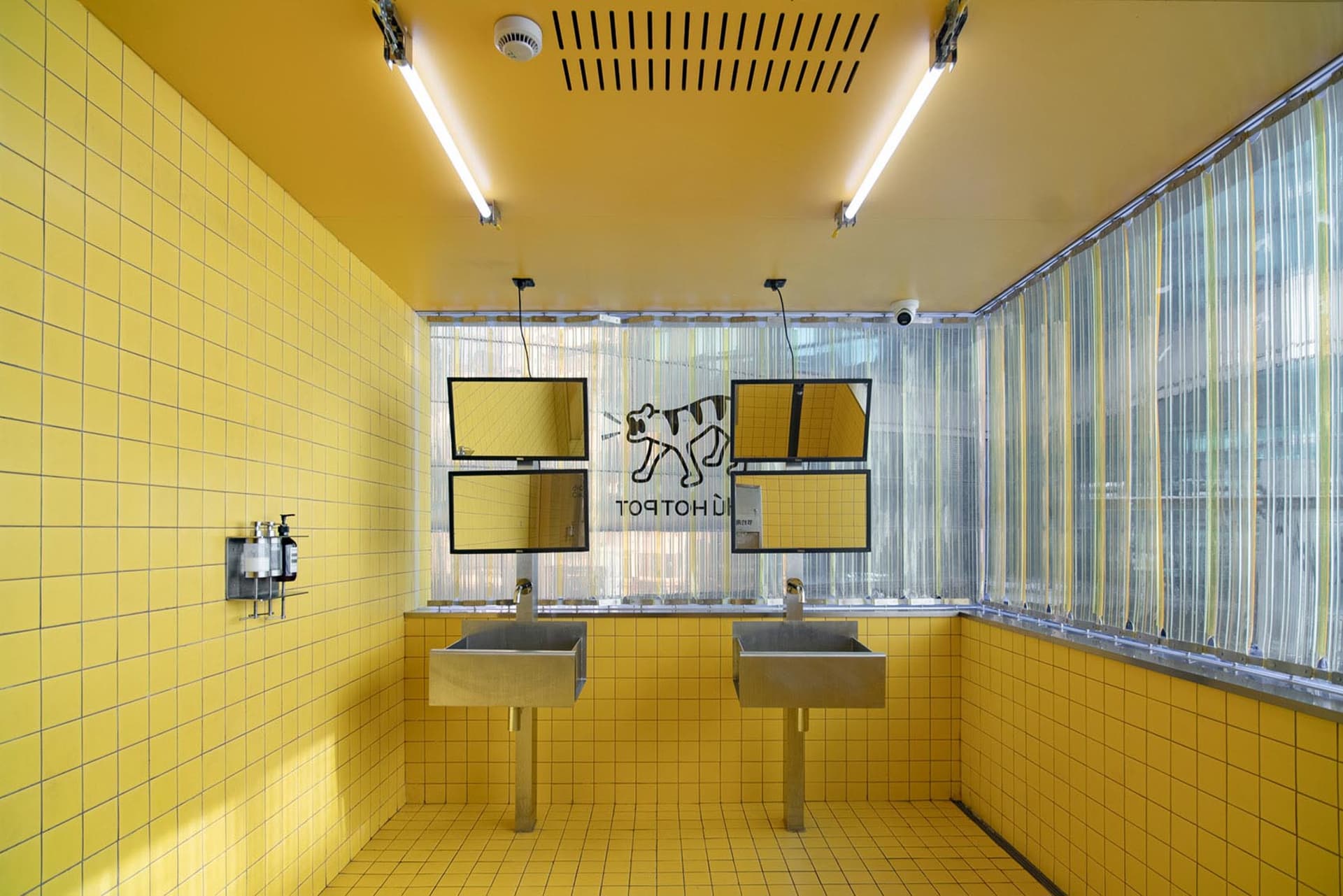 A public restroom with modern industrial design featuring yellow tiles and yellow walls