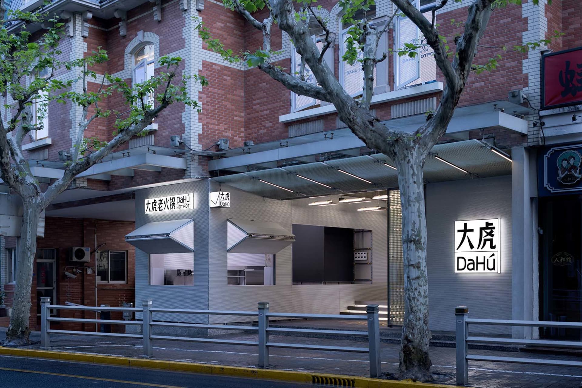 A modern restaurant exterior with a concrete facade, glass windows, and metal railings.
