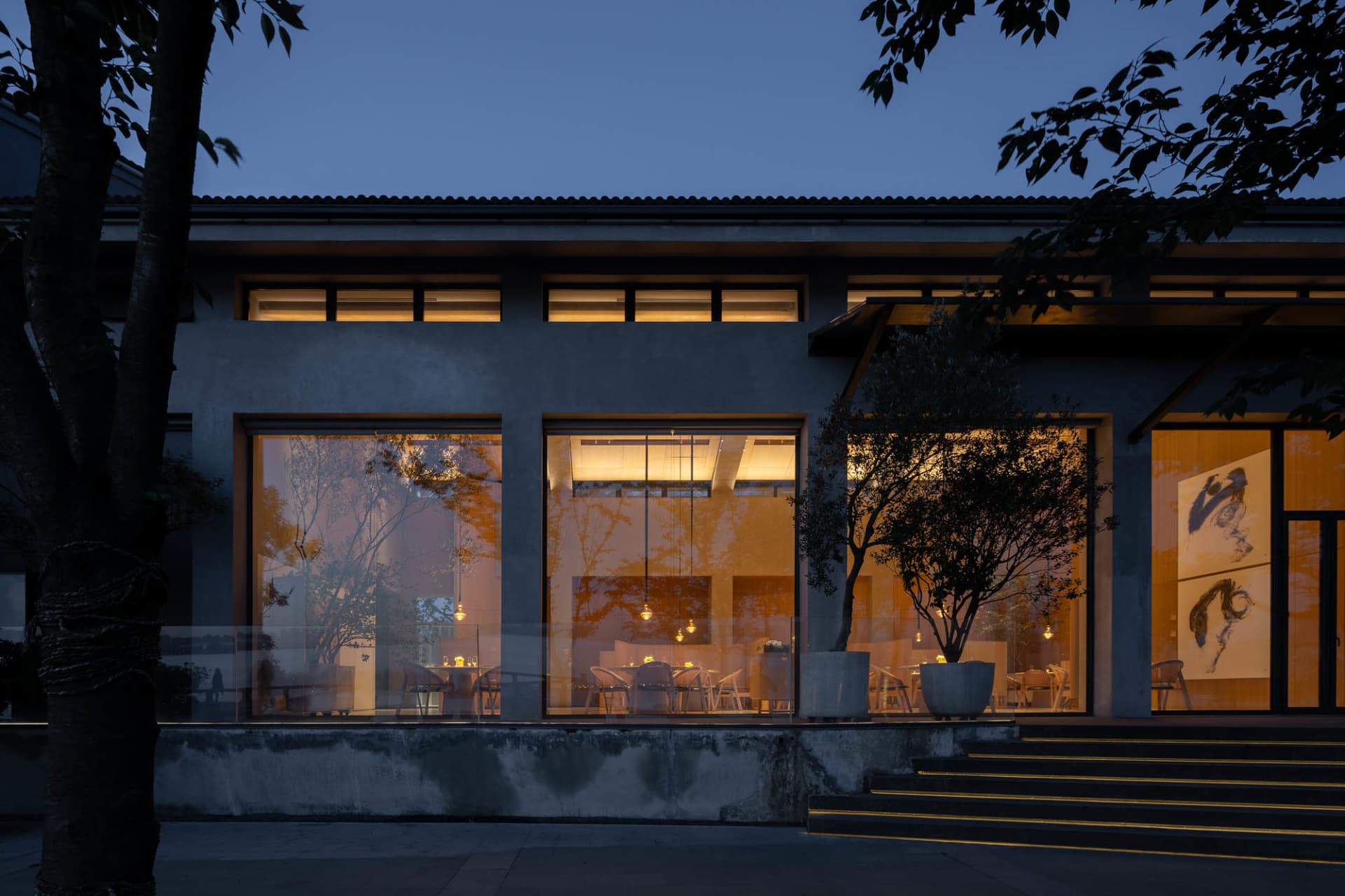 Modern restaurant exterior with concrete frame and glass windows at night