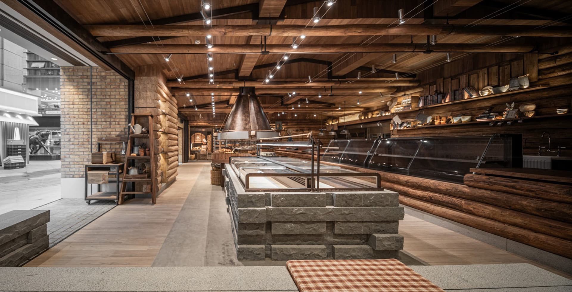 Interior view of an industrial-style restaurant featuring exposed brick walls, wooden beams, and stone accents.