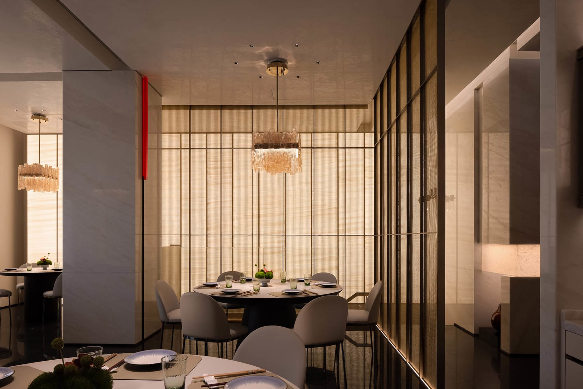 A modern minimalist restaurant interior with fabric curtains, metallic accents, and marble tables and chairs.