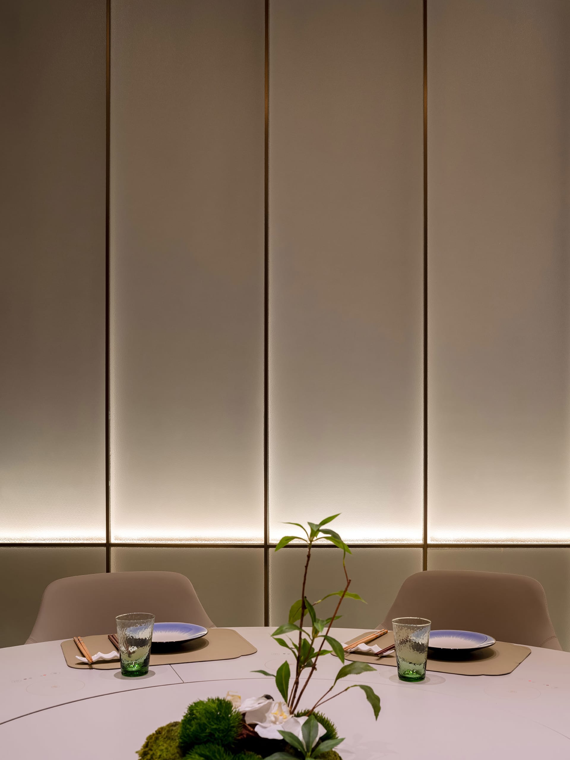 A well-dressed table setting in a modern restaurant, featuring minimalist design elements and a green plant centerpiece.