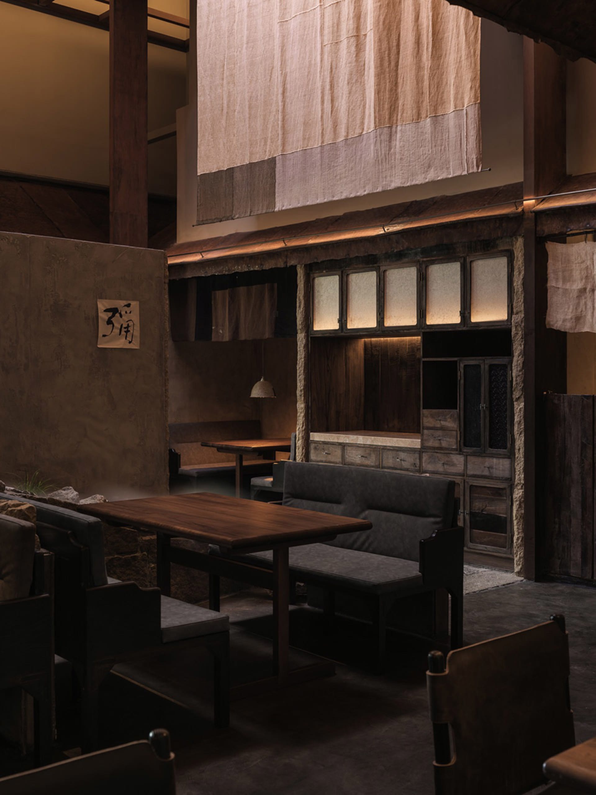 工業風主題的餐廳室內,搭配木質餐桌、石材牆面與布簾。