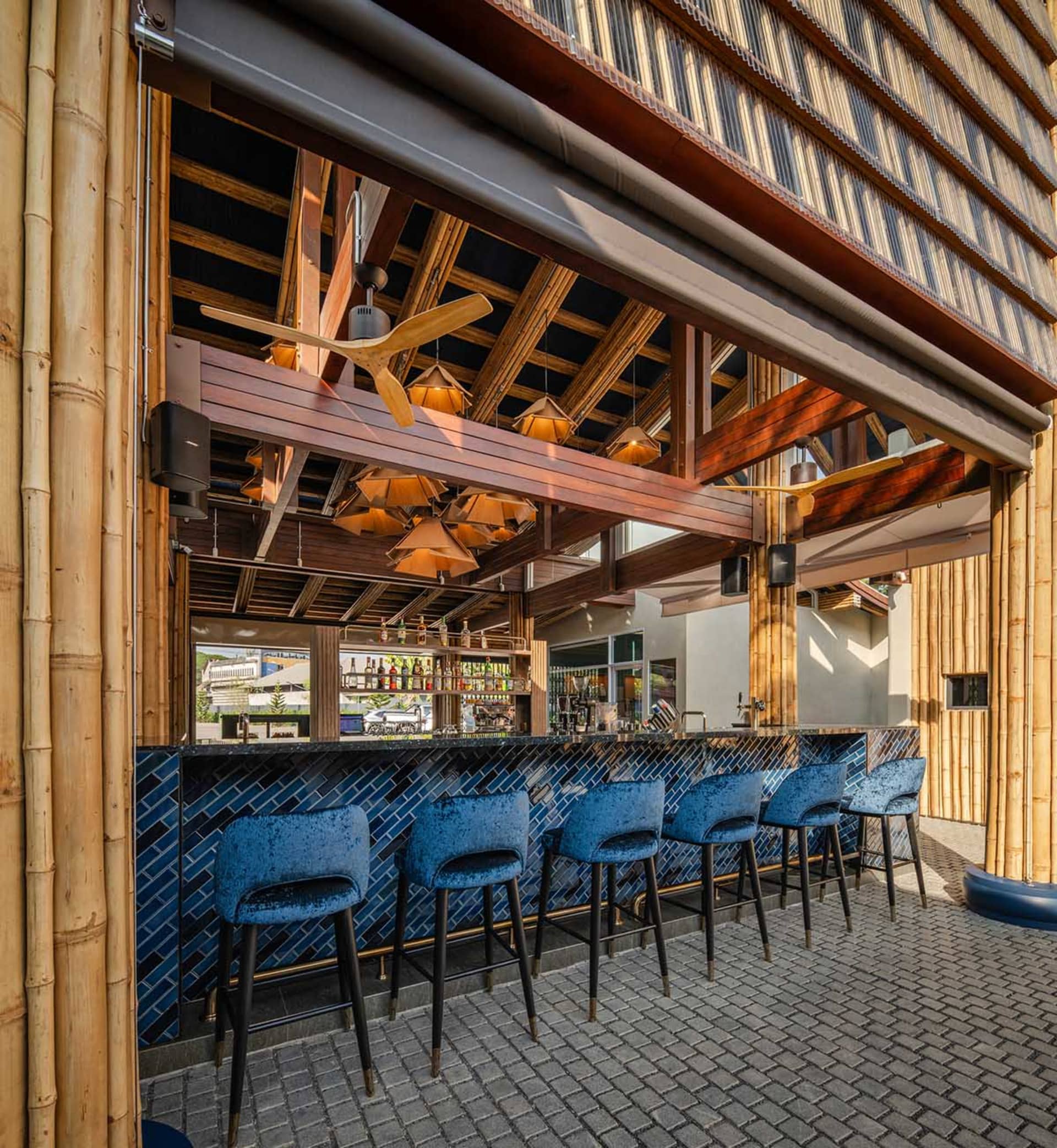 Interior of a restaurant bar featuring wooden beams, concrete flooring, and blue tiles
