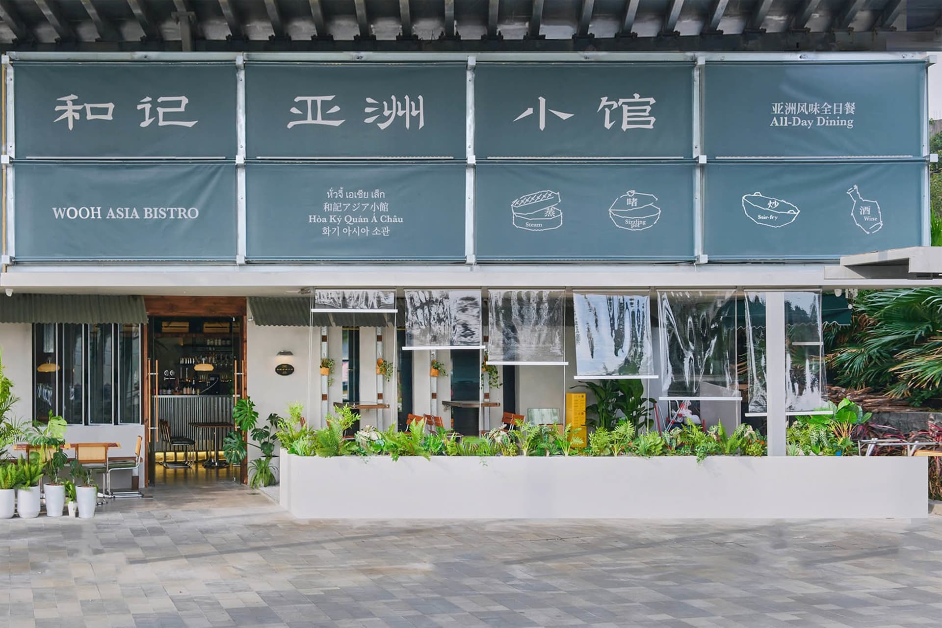 Front exterior view of Wooh Asia Bistro, featuring concrete, glass, and greenery.