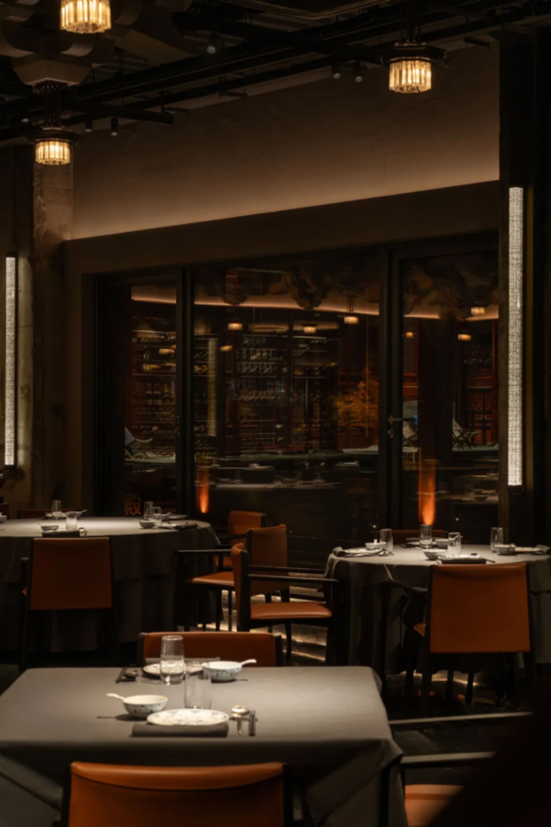 A minimalist restaurant interior featuring black glass tables and modern furniture.