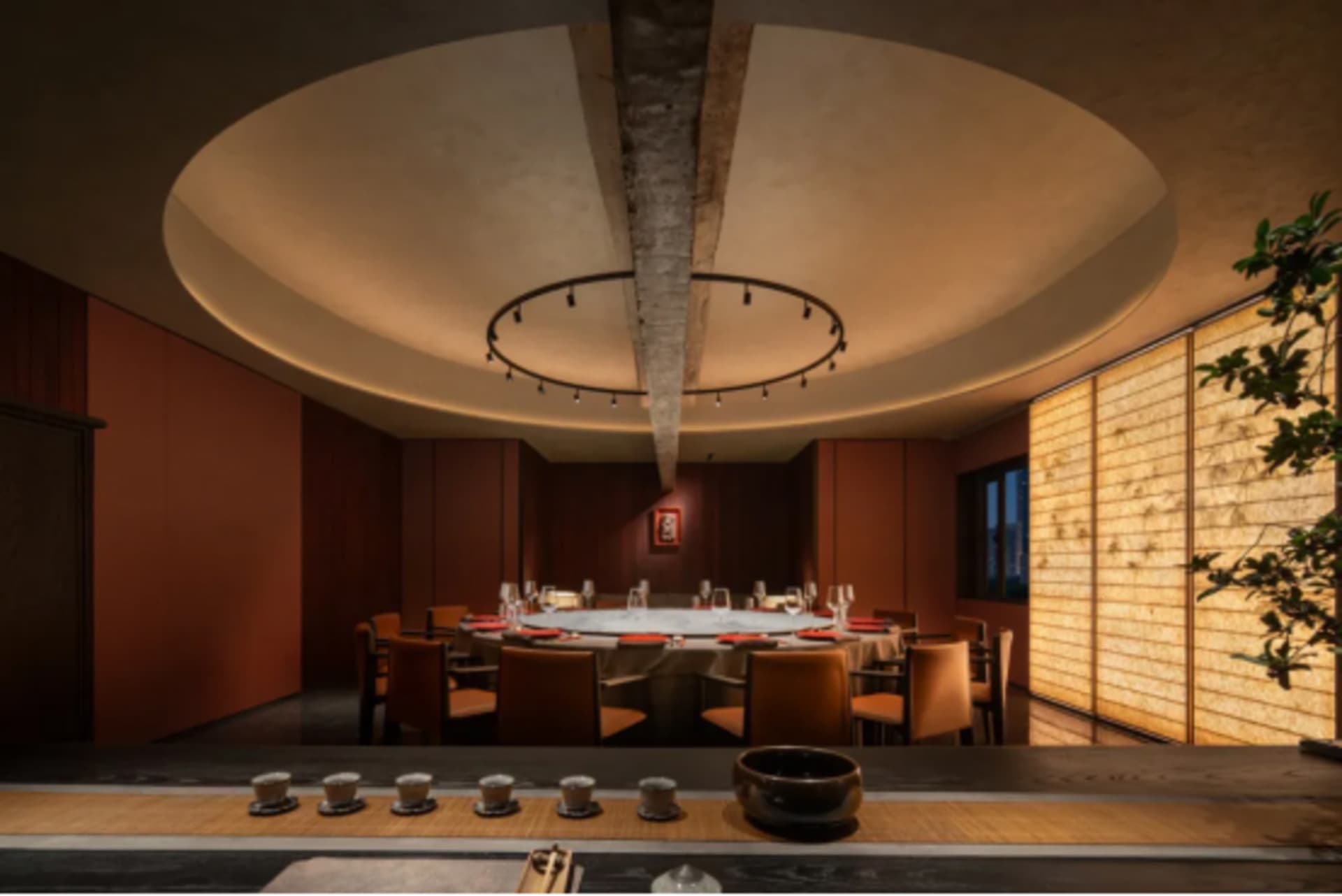 An elegant, modern restaurant interior with wooden elements and a circular ceiling light fixture.