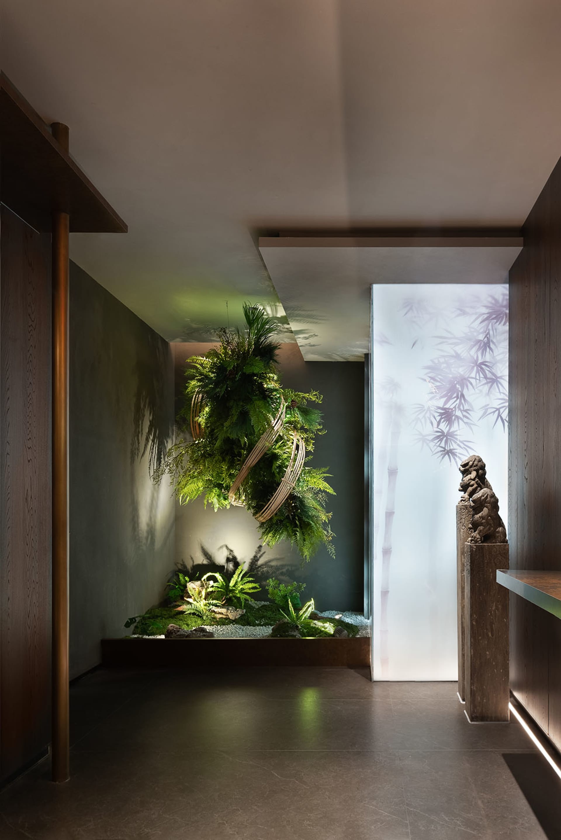 Lobby featuring minimalist design with greenery, wood, and concrete elements.