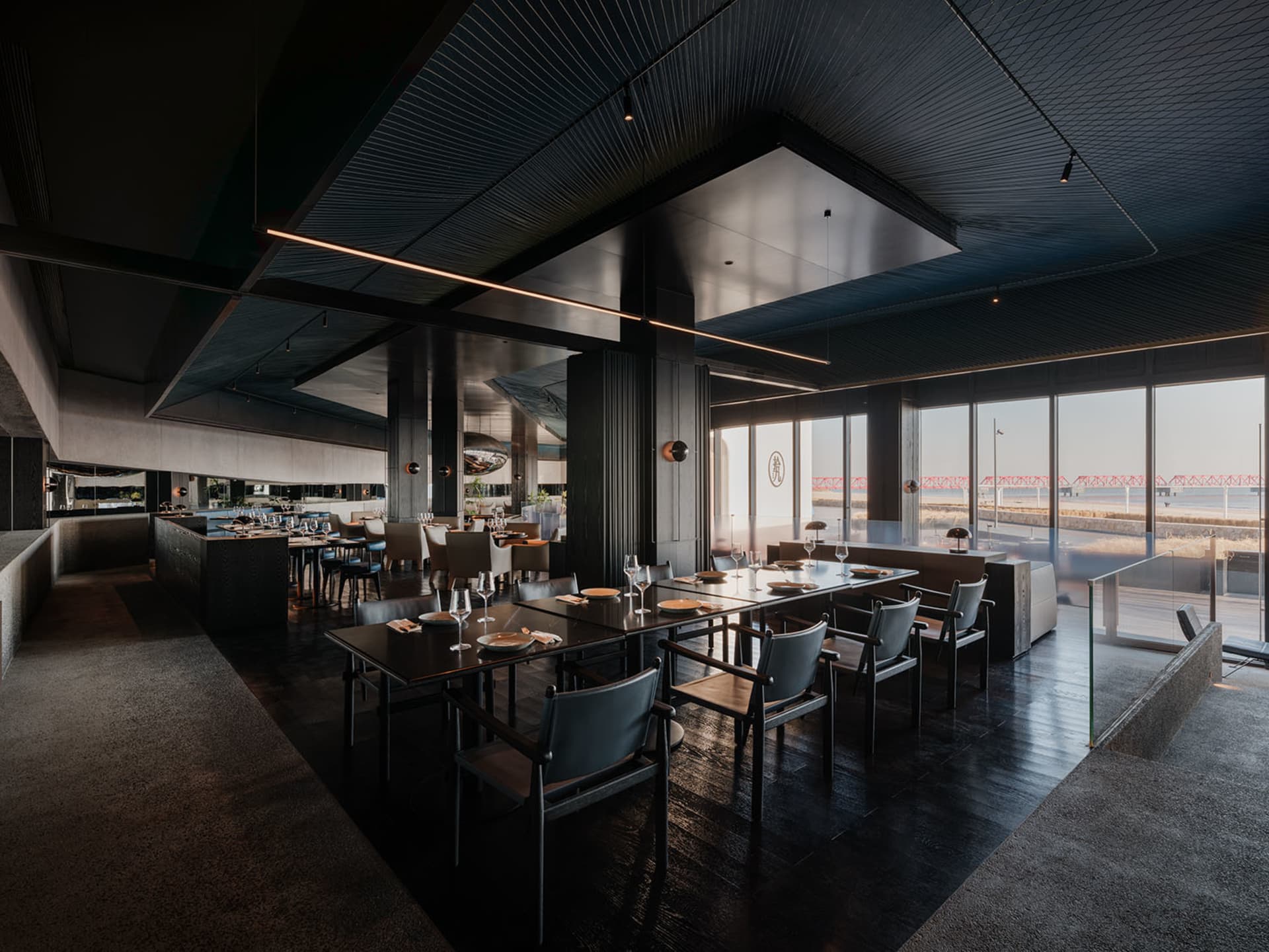 A modern restaurant interior with dark wood, glass, and metal elements