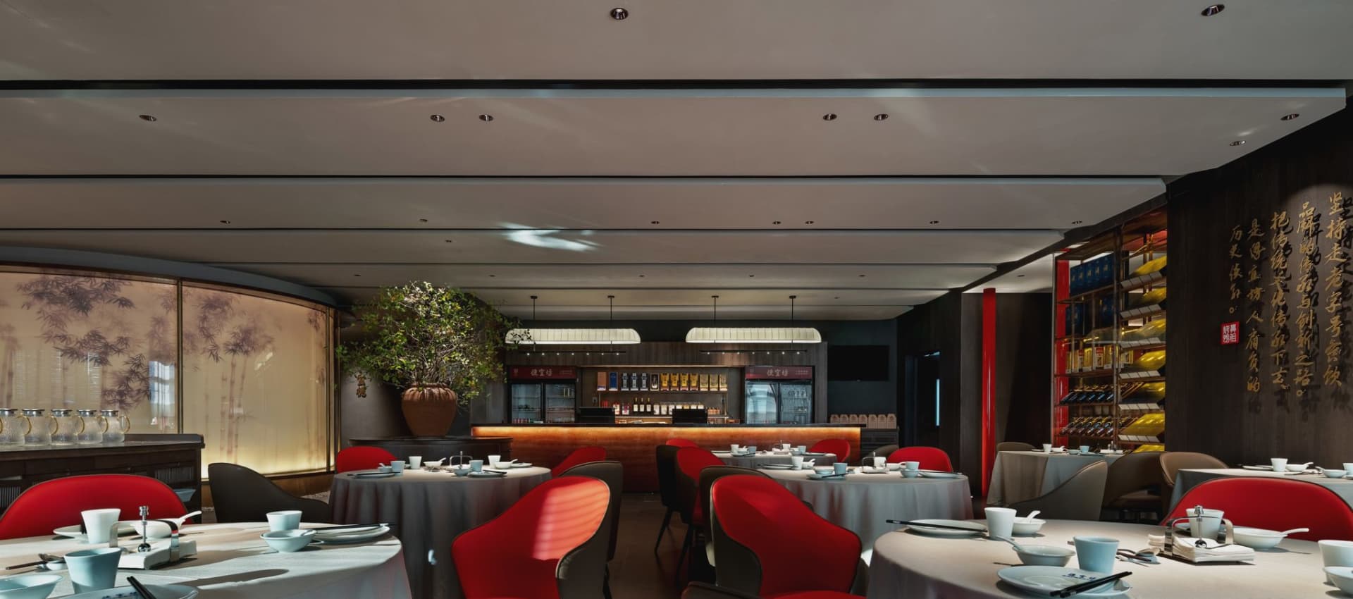 A modern restaurant interior featuring red leather furniture and white tablecloths.