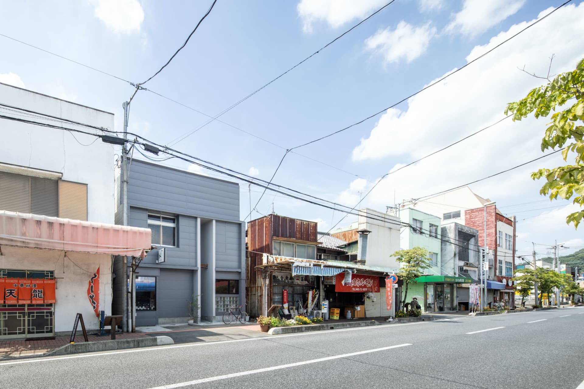A street view of a concrete urban setting with shops and buildings along the road.
