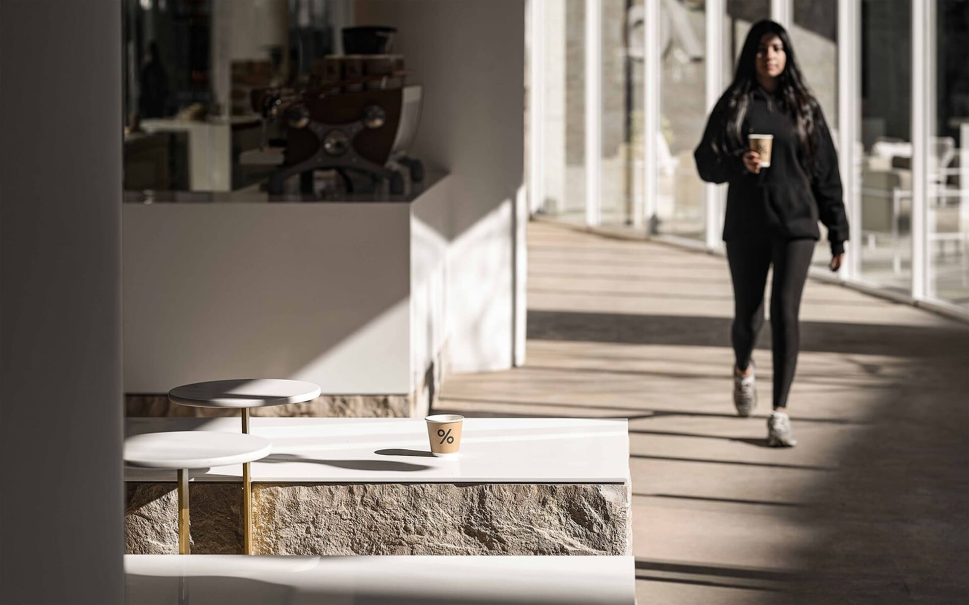 A minimalist coffee shop with a clean, white countertop featuring a take-out coffee cup with a percentage symbol.
