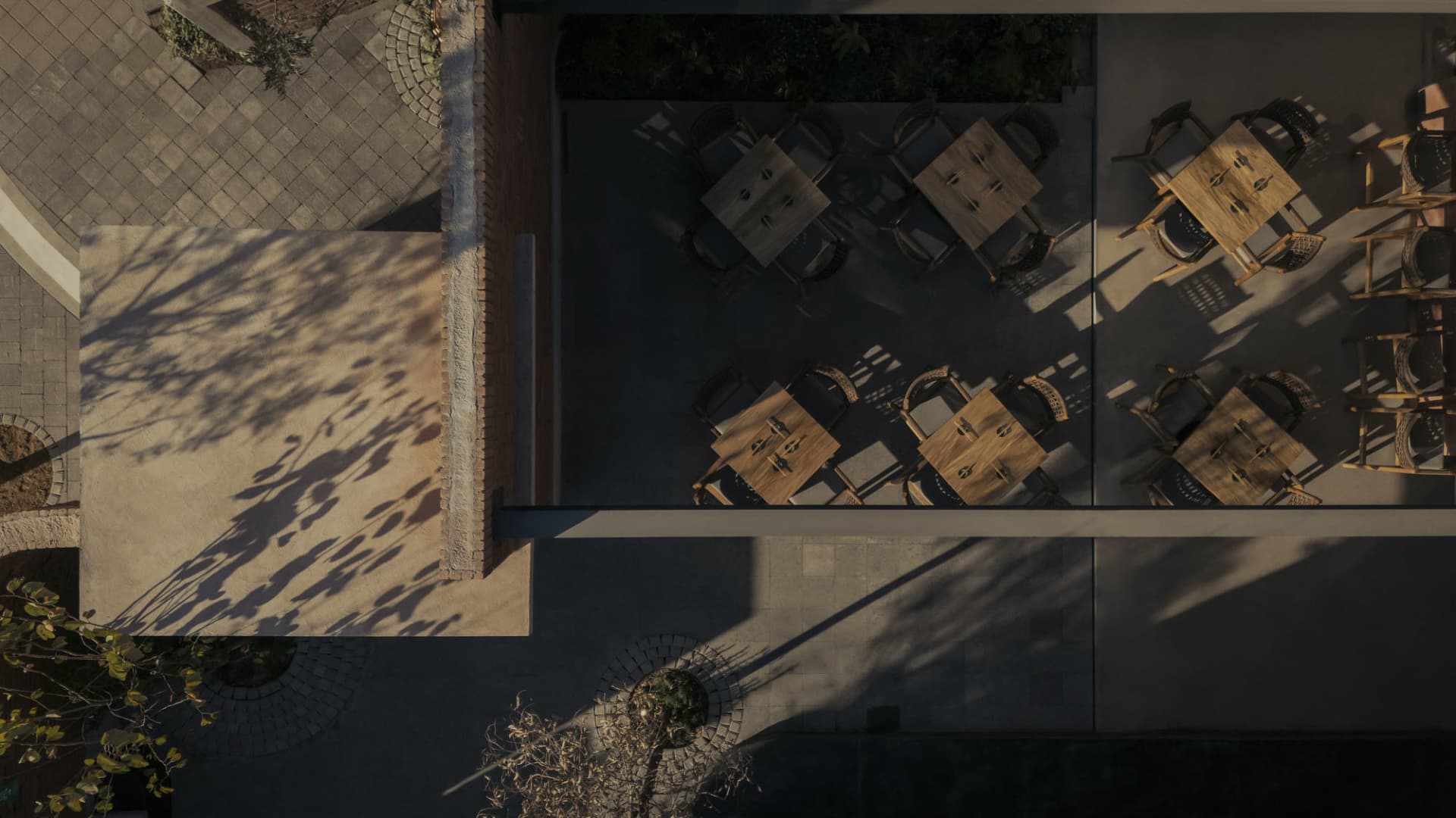 Aerial view of a restaurant exterior featuring wooden tables, concrete patio, and tiled flooring.