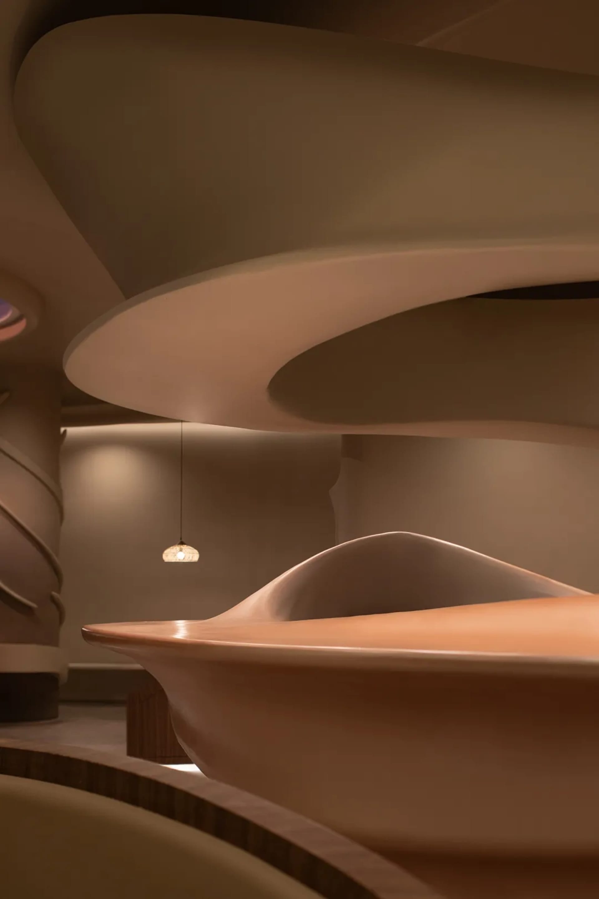 A modern interior space featuring a wooden sculpture with smooth, organic shapes.