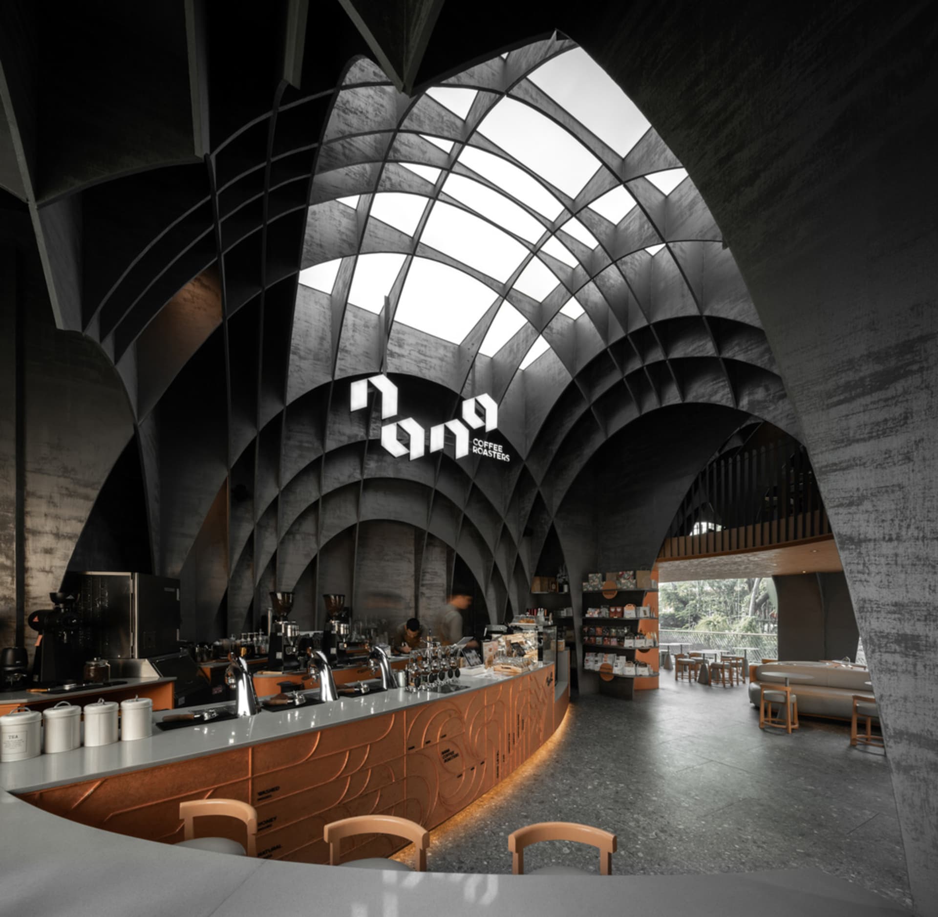 A modern, industrial-style coffee shop with concrete and metal finishes.