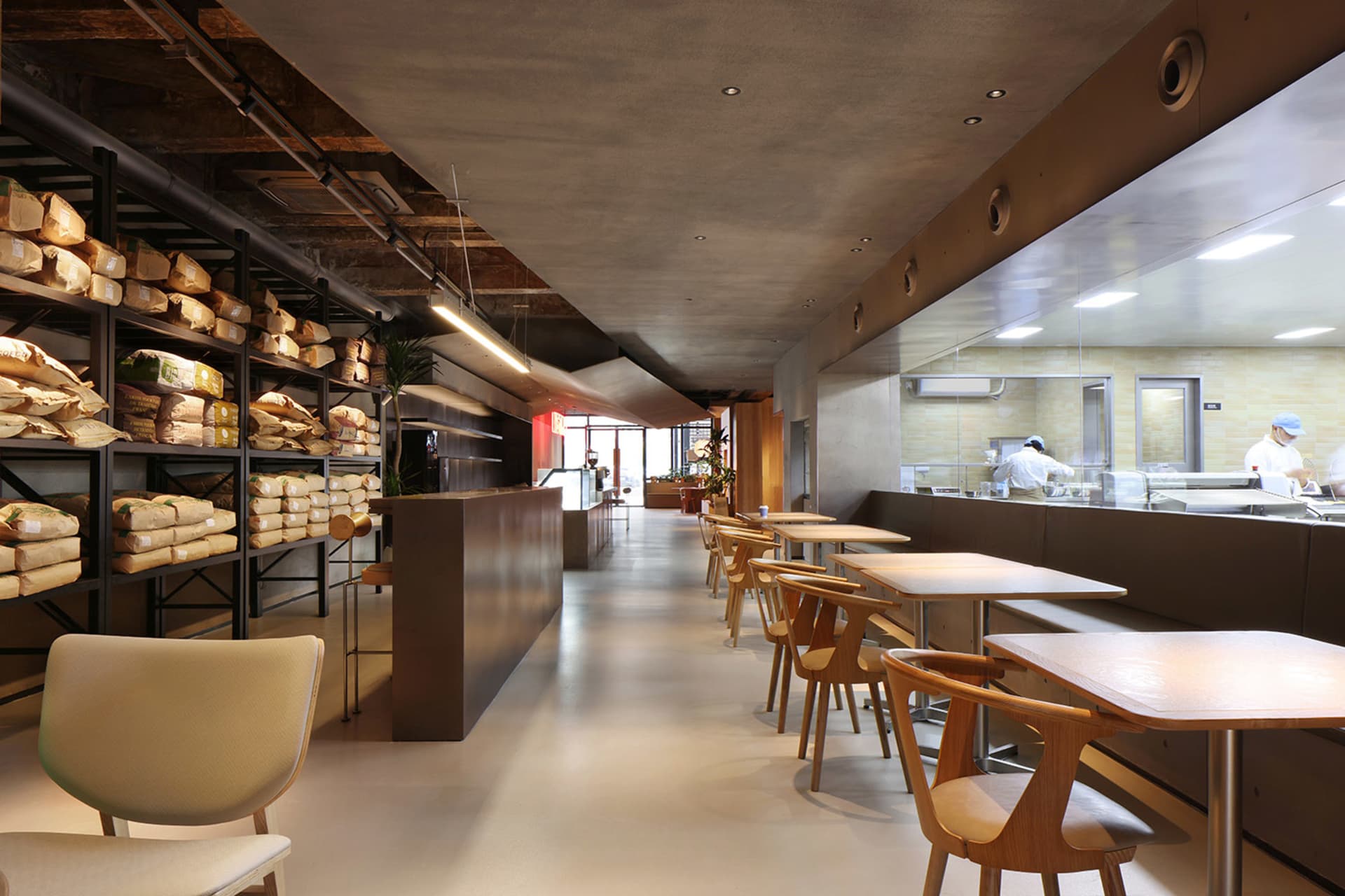 寬敞的工業風餐廳室內,鋪設混凝土地板,搭配木質家具與開放式座位區。