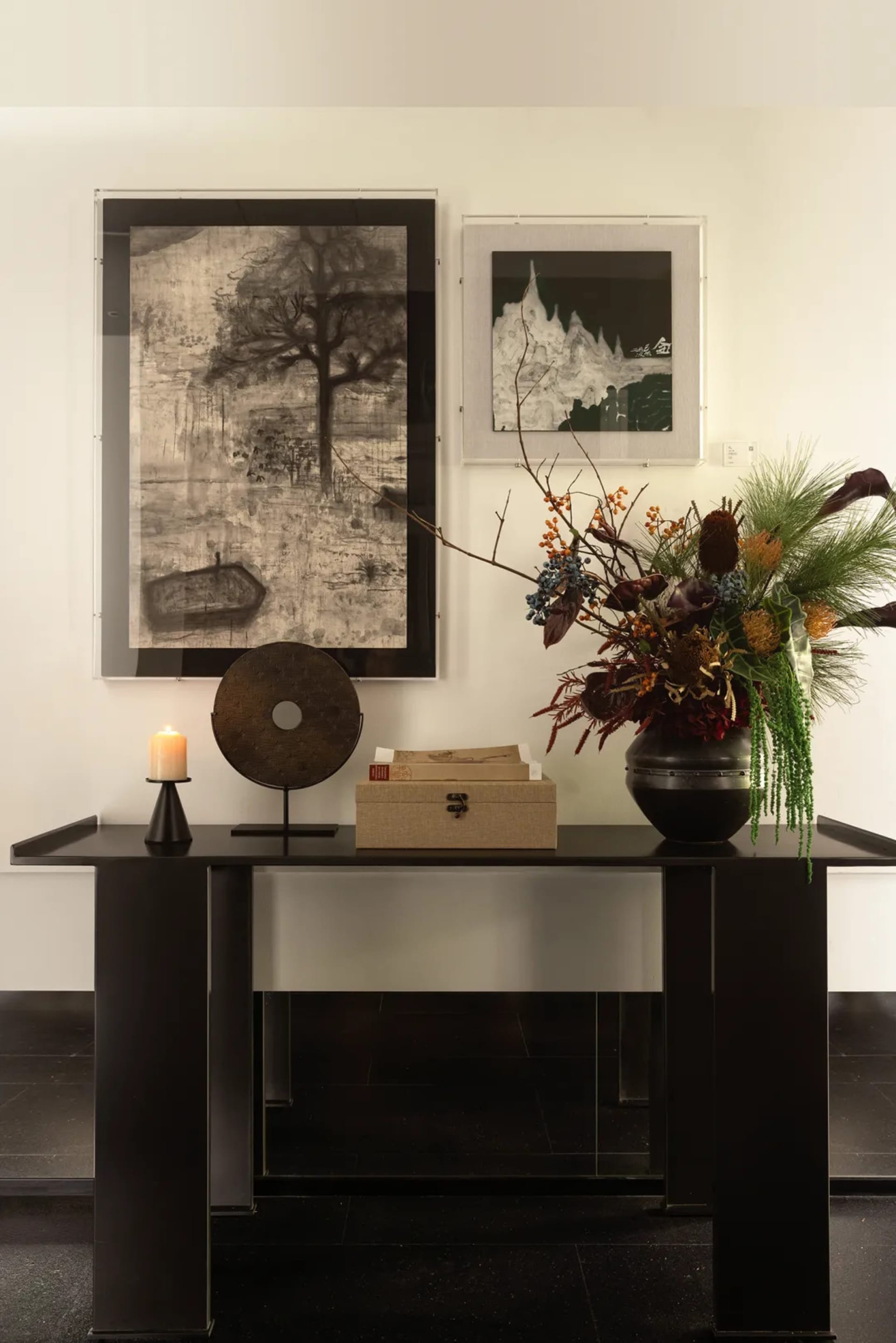 A black metal table with a vase of flowers, books, and a candle.