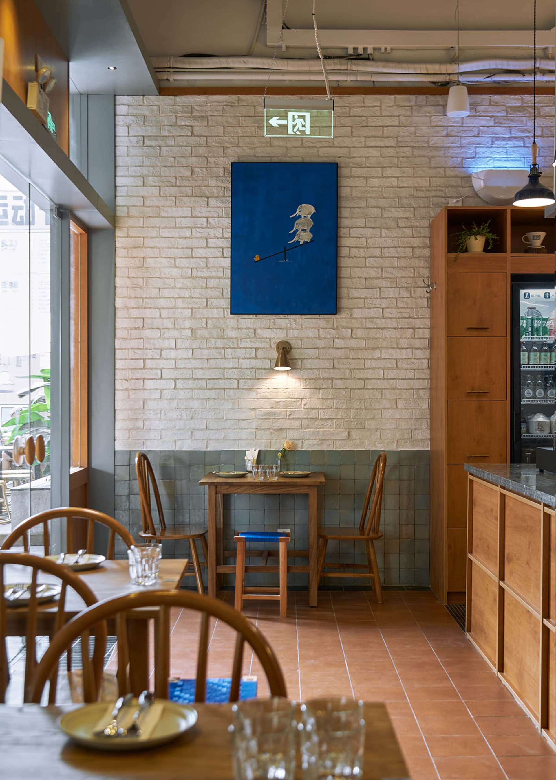 A cozy cafe interior with brick walls, wooden furniture, and tiled seating area.