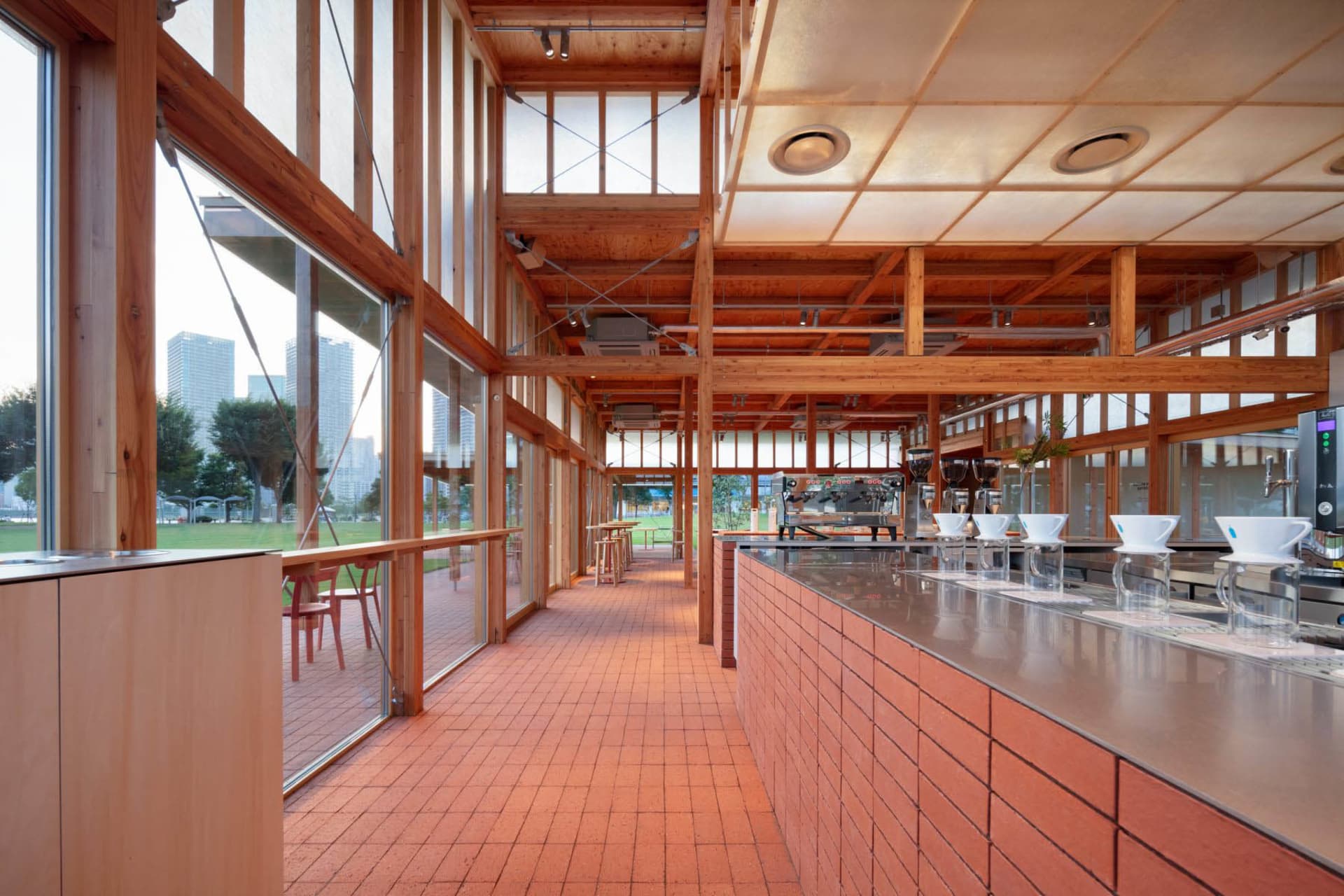 Interior of an industrial-style coffee shop with brick counter and open-air seating area.