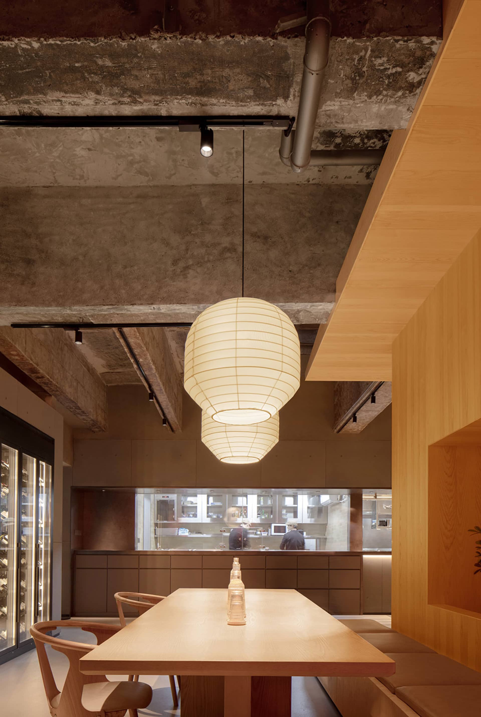 現代餐廳室內，設有用餐區，搭配木質桌椅、混凝土牆面及吊燈照明。