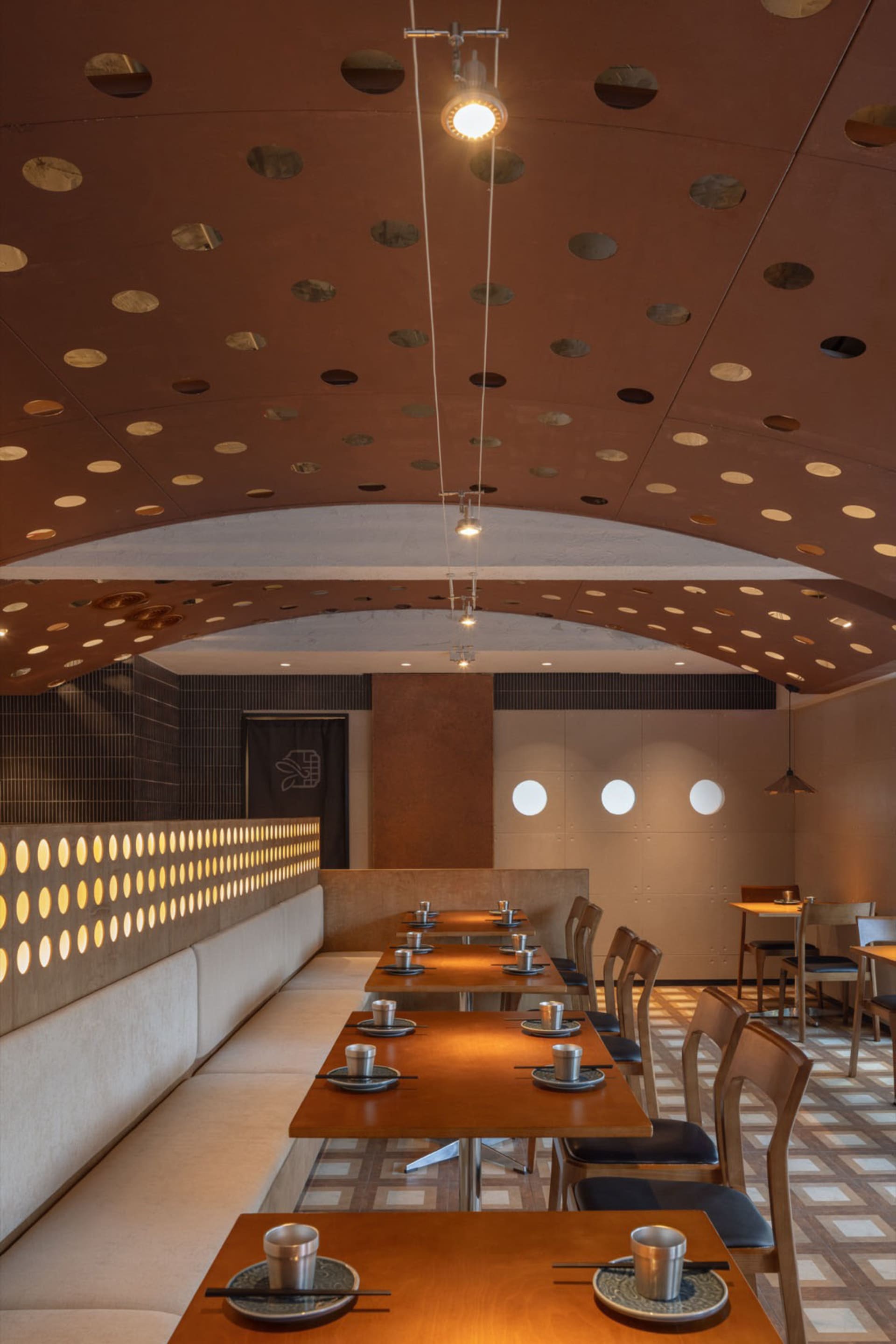 Modern restaurant interior featuring wooden tables, metallic accents, and ceramic elements.