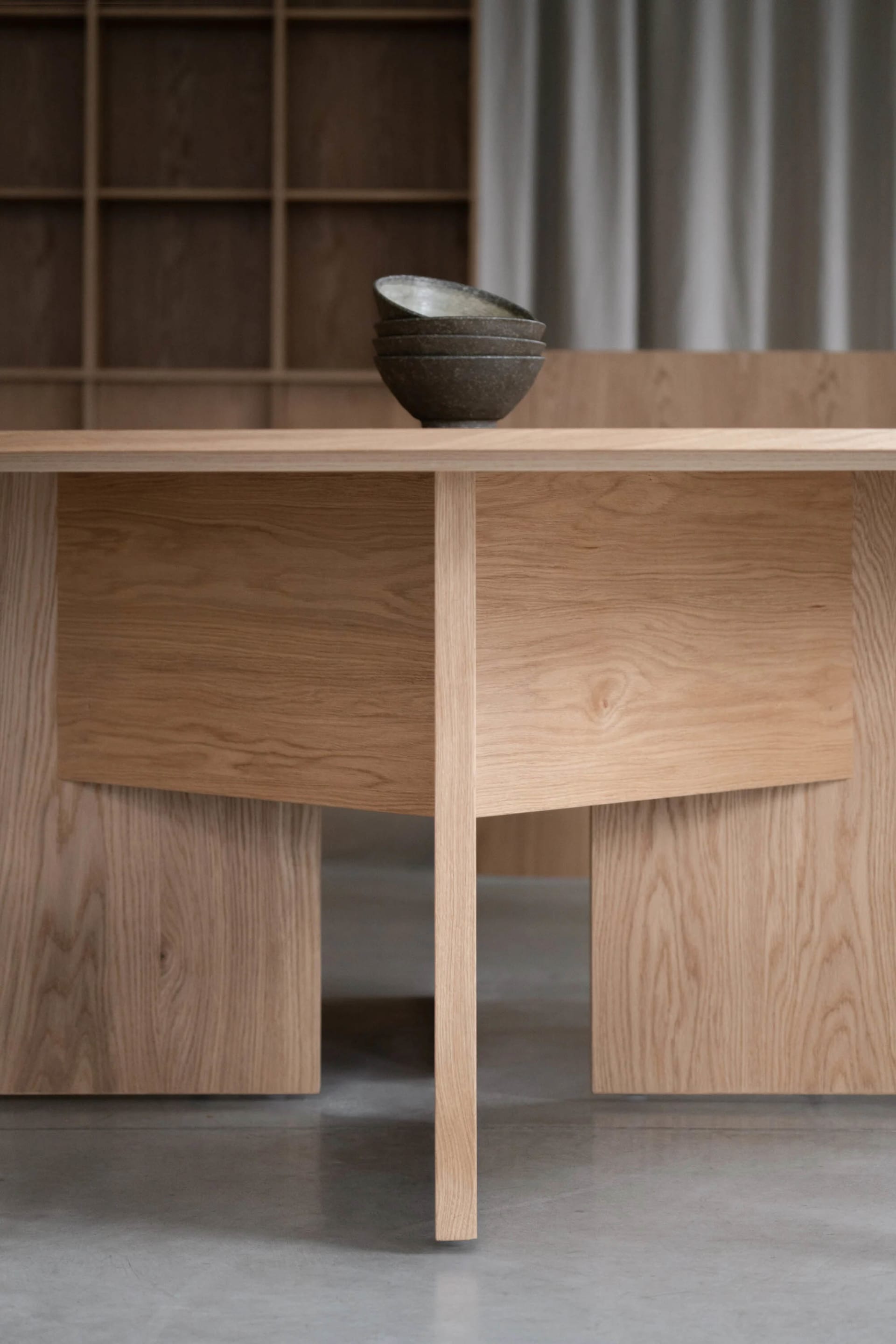 Modern dining room featuring an oak wood table and stacked black bowls.