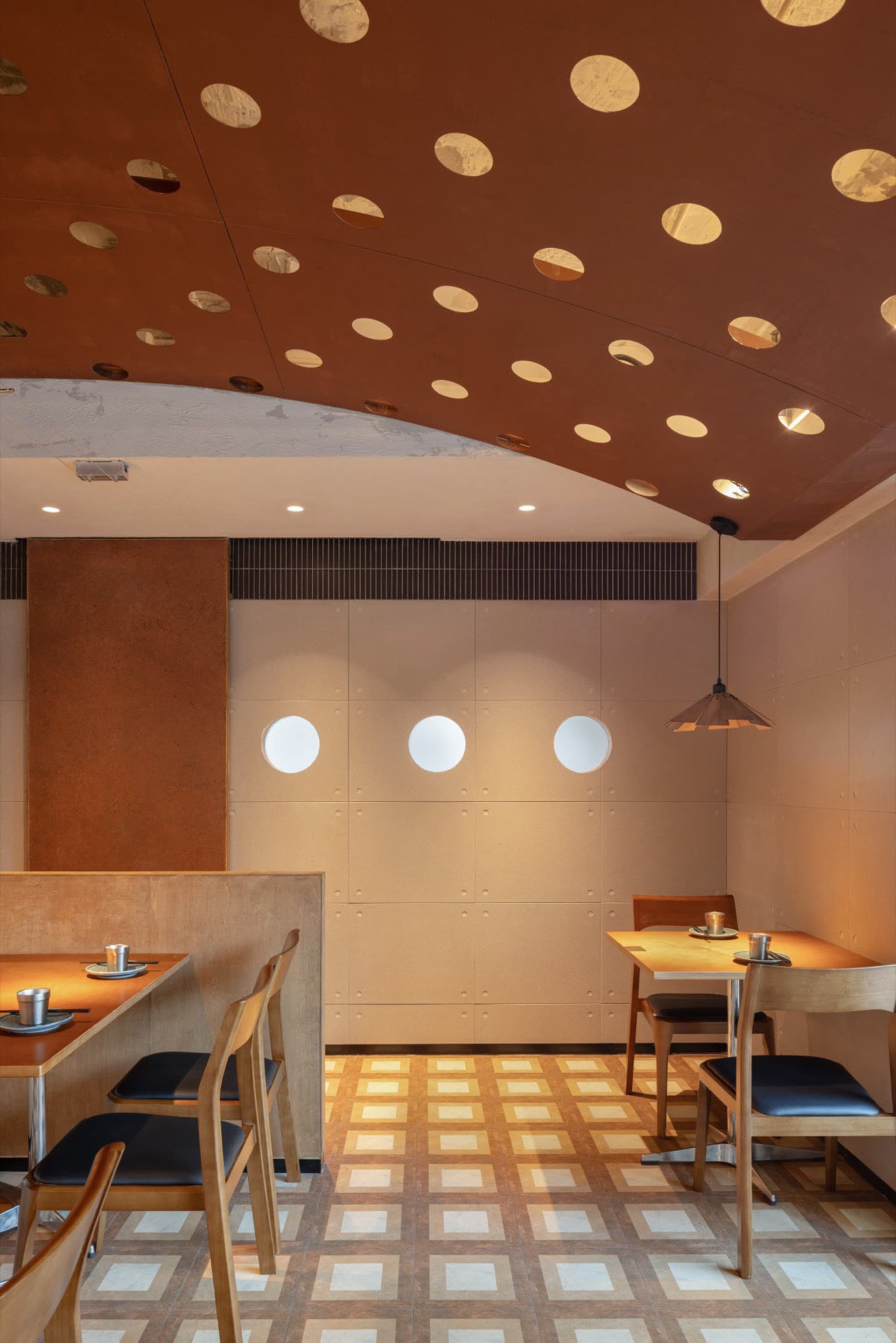 Modern industrial restaurant interior with wood tables, metal accents, and patterned floor.