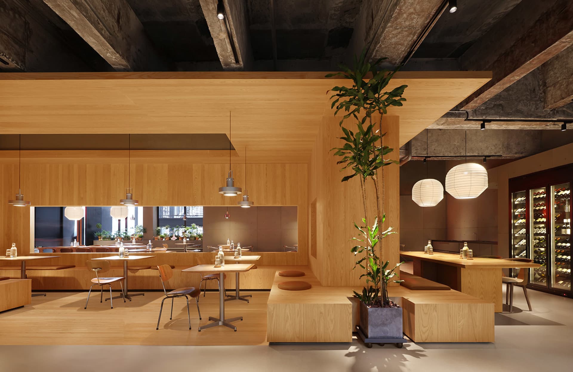 現代餐廳室內，木質牆面、餐桌與座位區，搭配植物與吊掛燈籠式燈具。