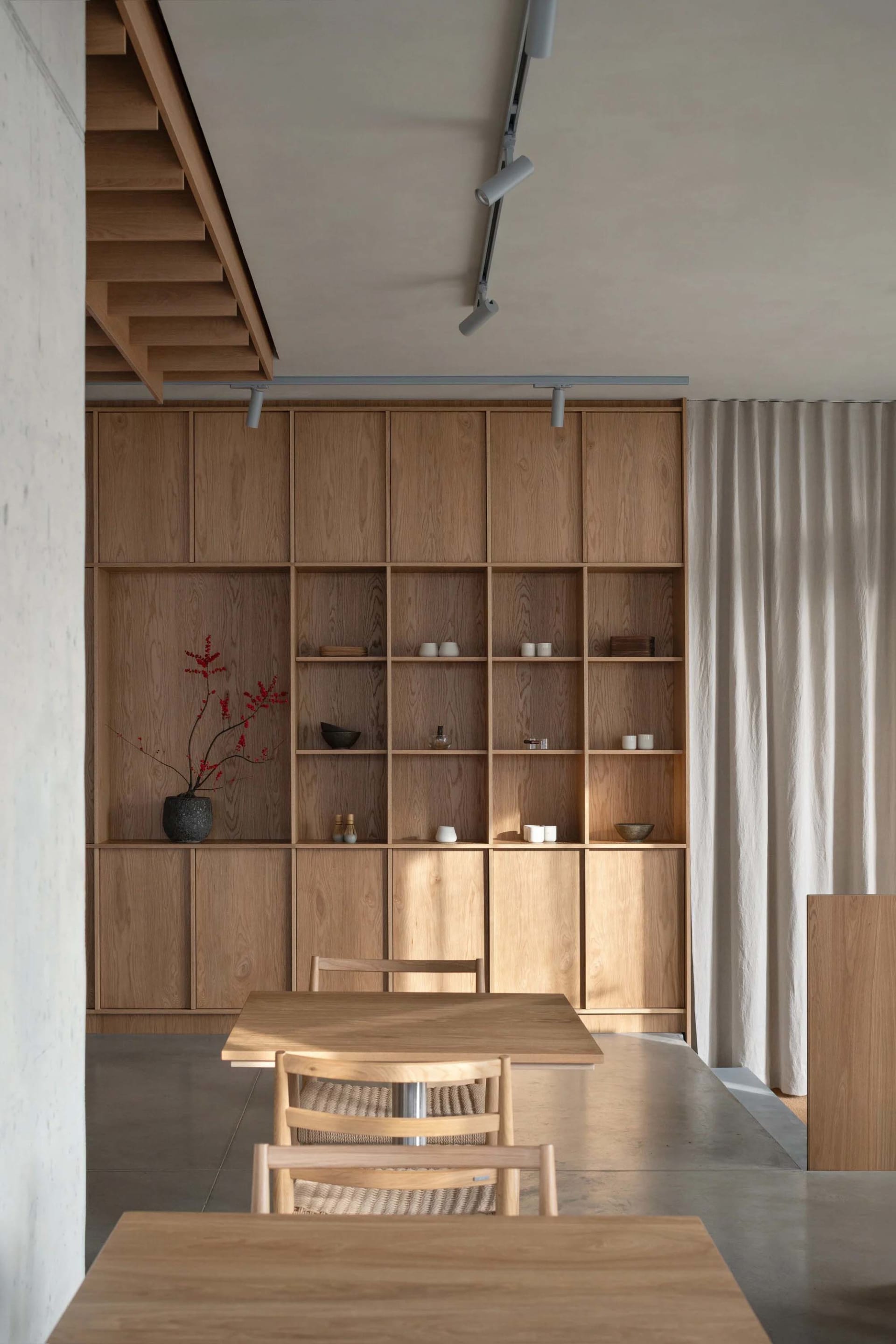 A modern dining room with wooden furniture and built-in shelves.