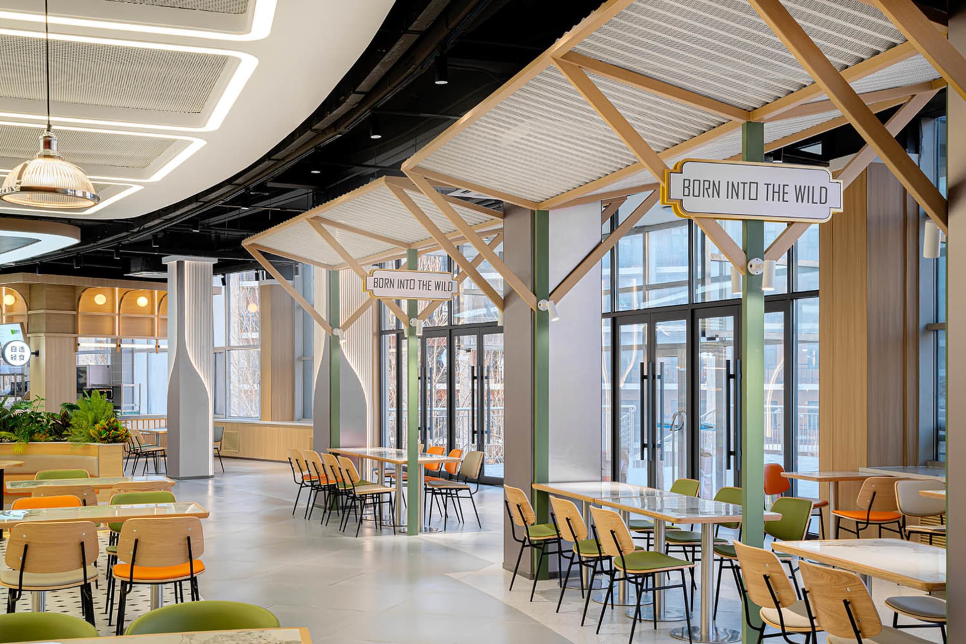 A minimalist cafeteria interior with light-colored wooden furniture, open-air design, and modern signage.