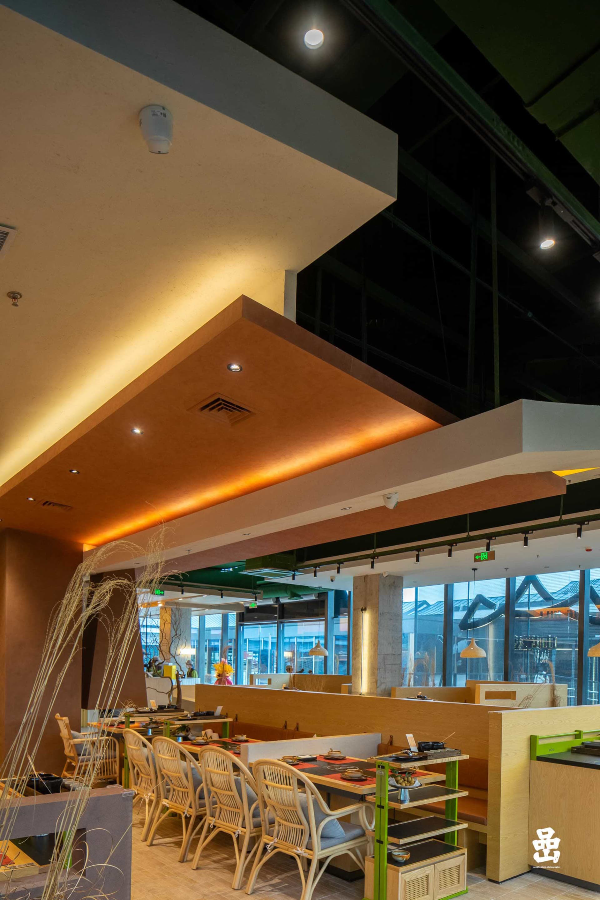 A modern restaurant interior featuring concrete walls and wooden seating.