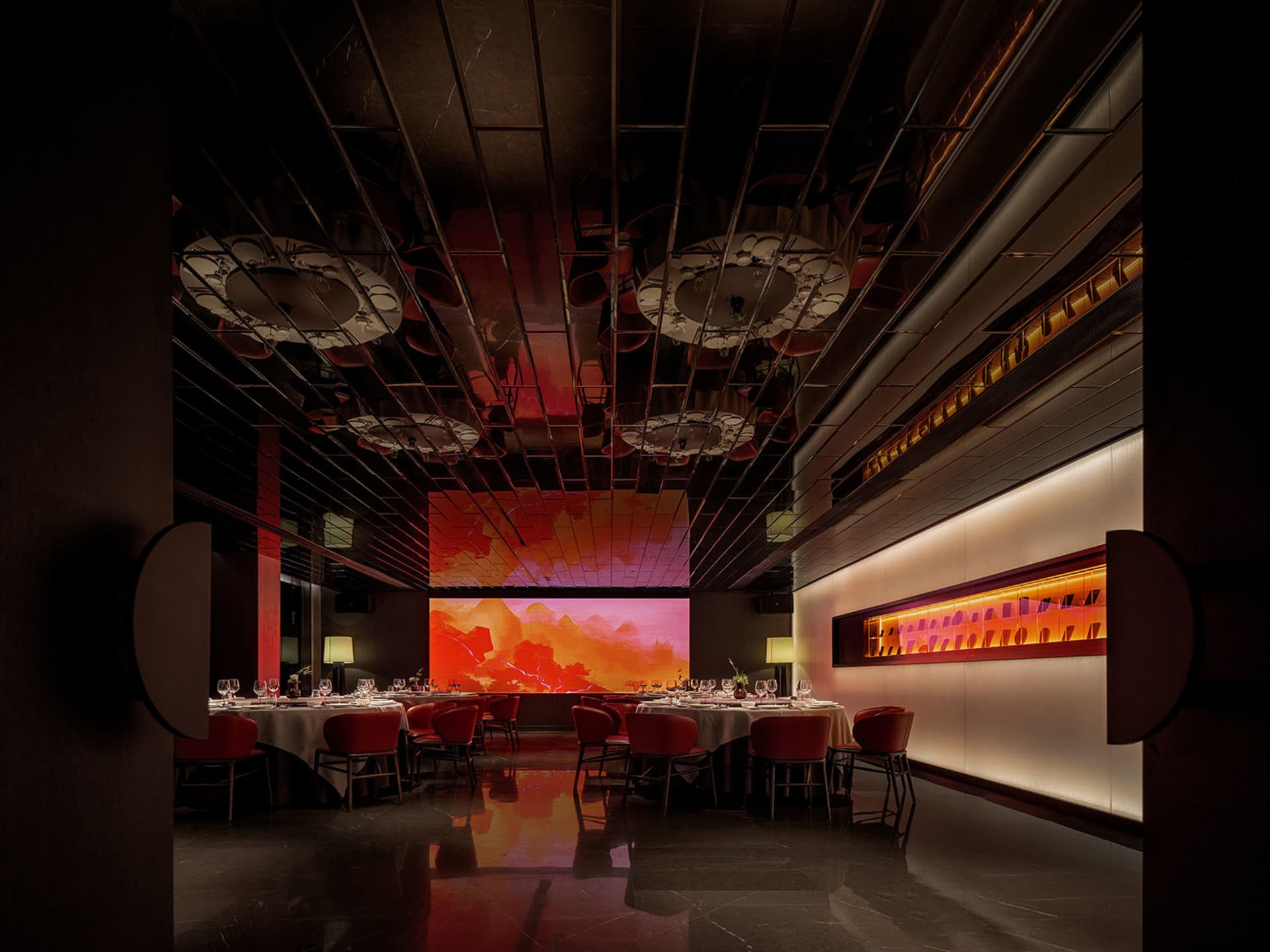 A modern restaurant interior featuring metallic and plastic materials with a large digital display of a scenic landscape.