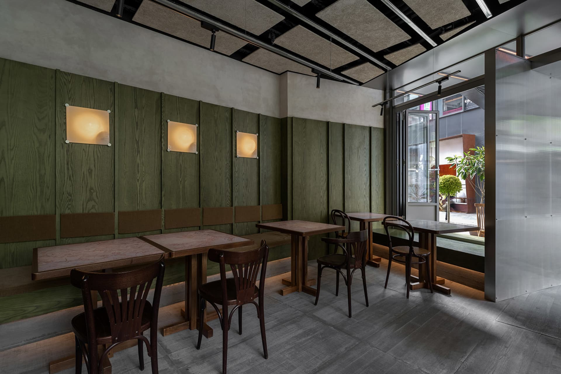 Industrial restaurant interior with green wooden walls, wooden tables, and chairs.