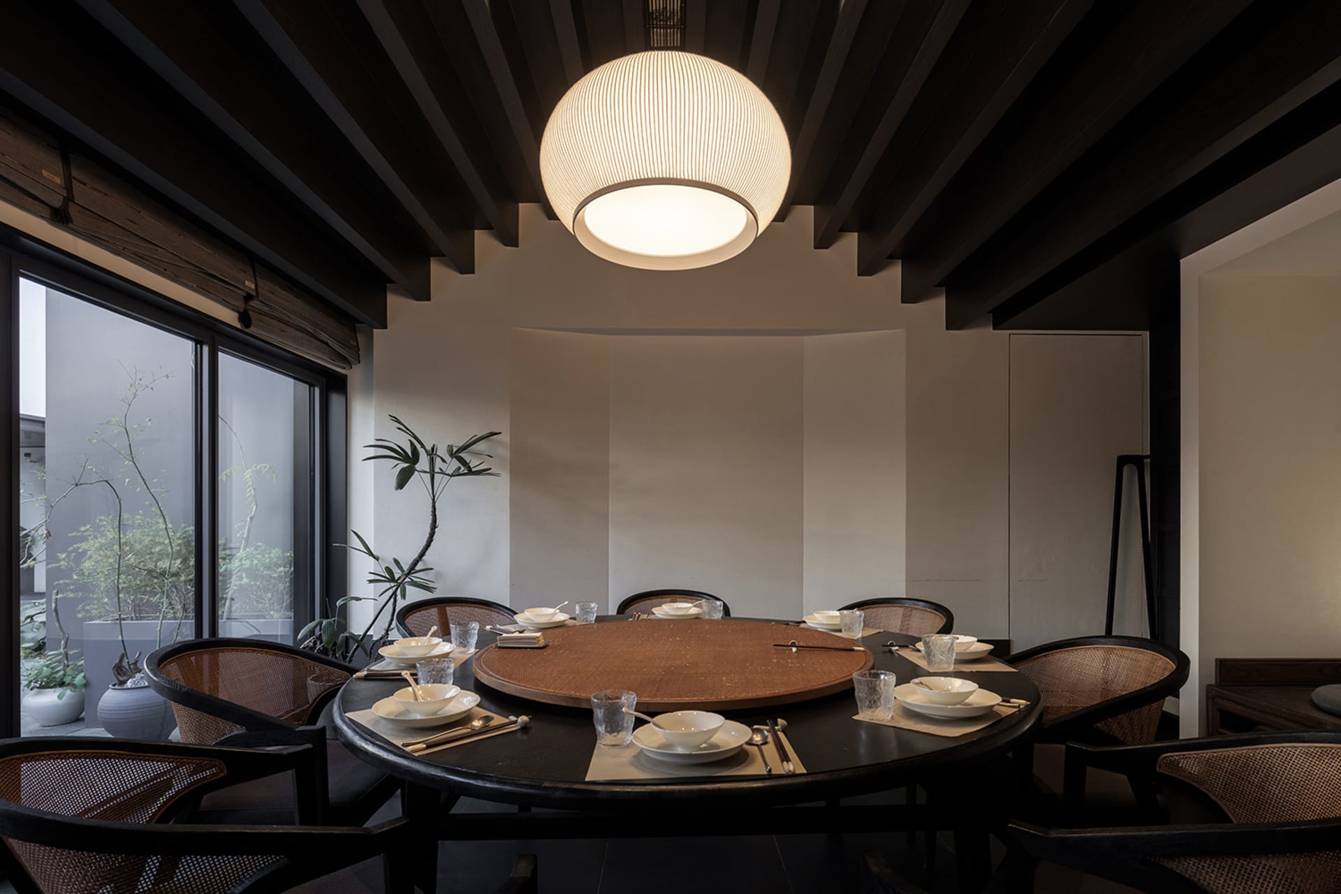 A minimalist dining room featuring wooden furniture and a round table.