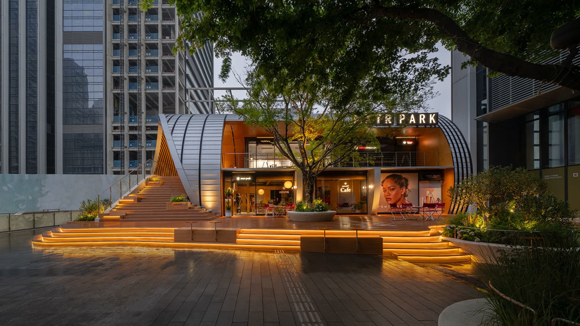 Modern storefront with metallic architectural elements and illuminated signage.