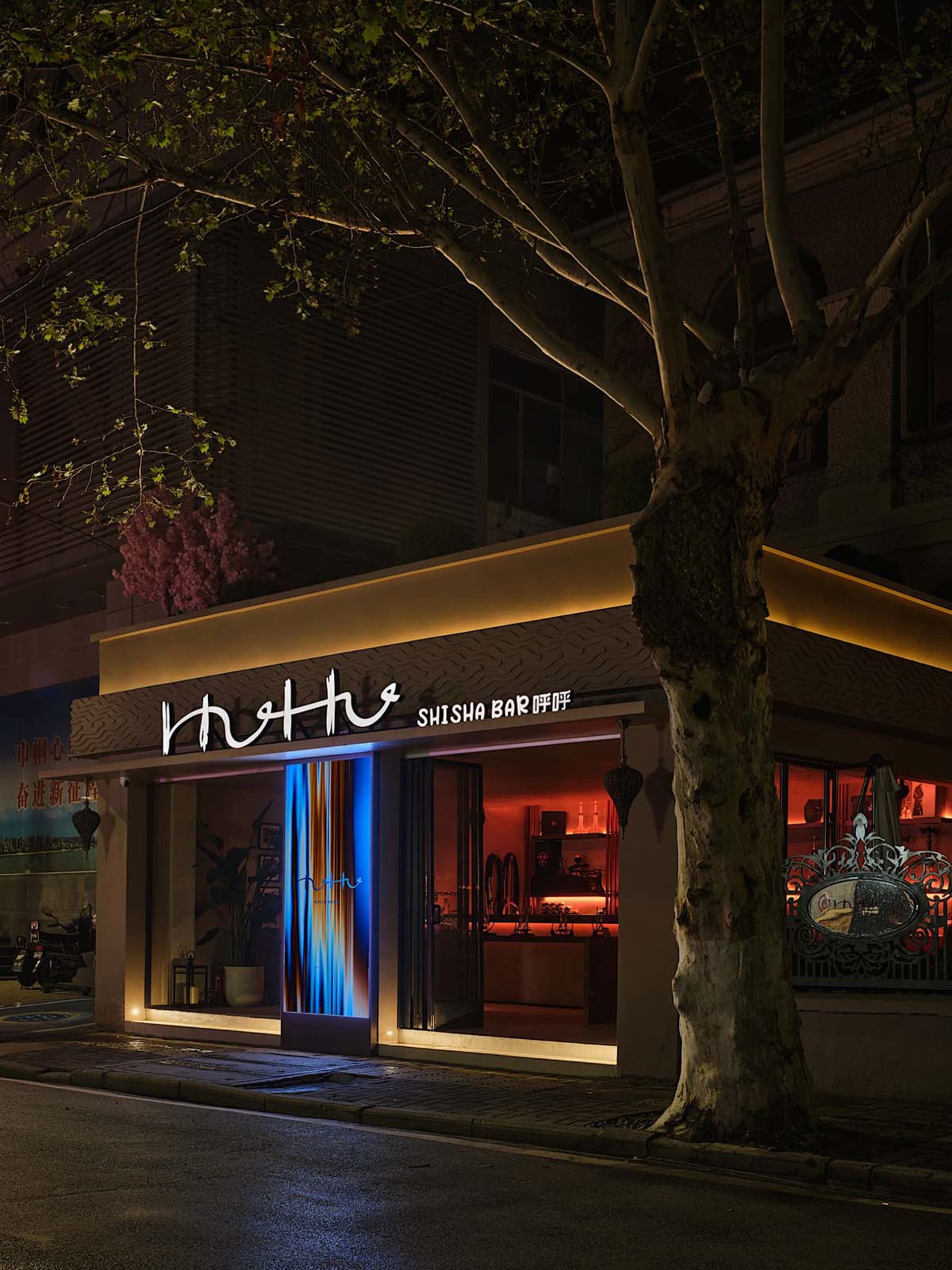 A modern bar storefront with illuminated lights and concrete facade