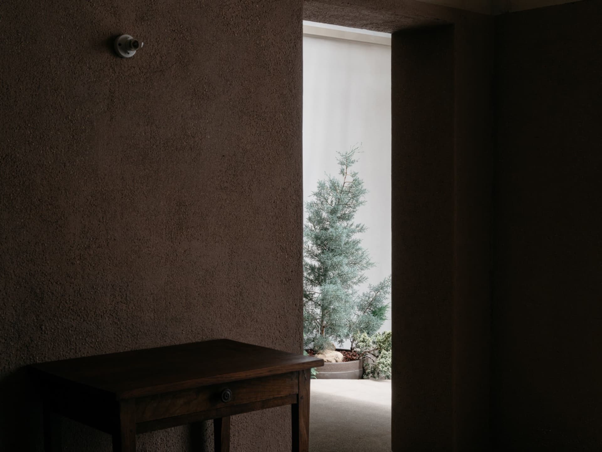 A minimalist interior with concrete walls and a wooden table.