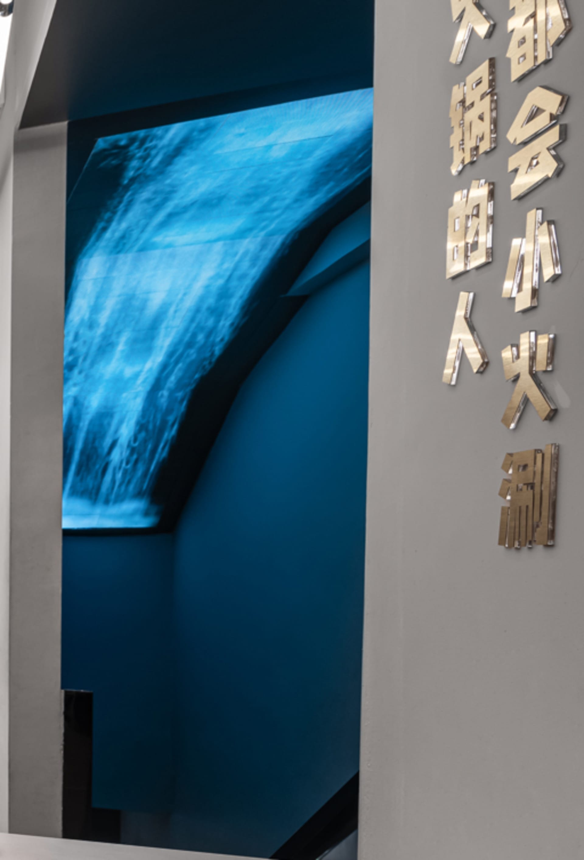 A modern architectural installation featuring a waterfall and illuminated lighting elements.