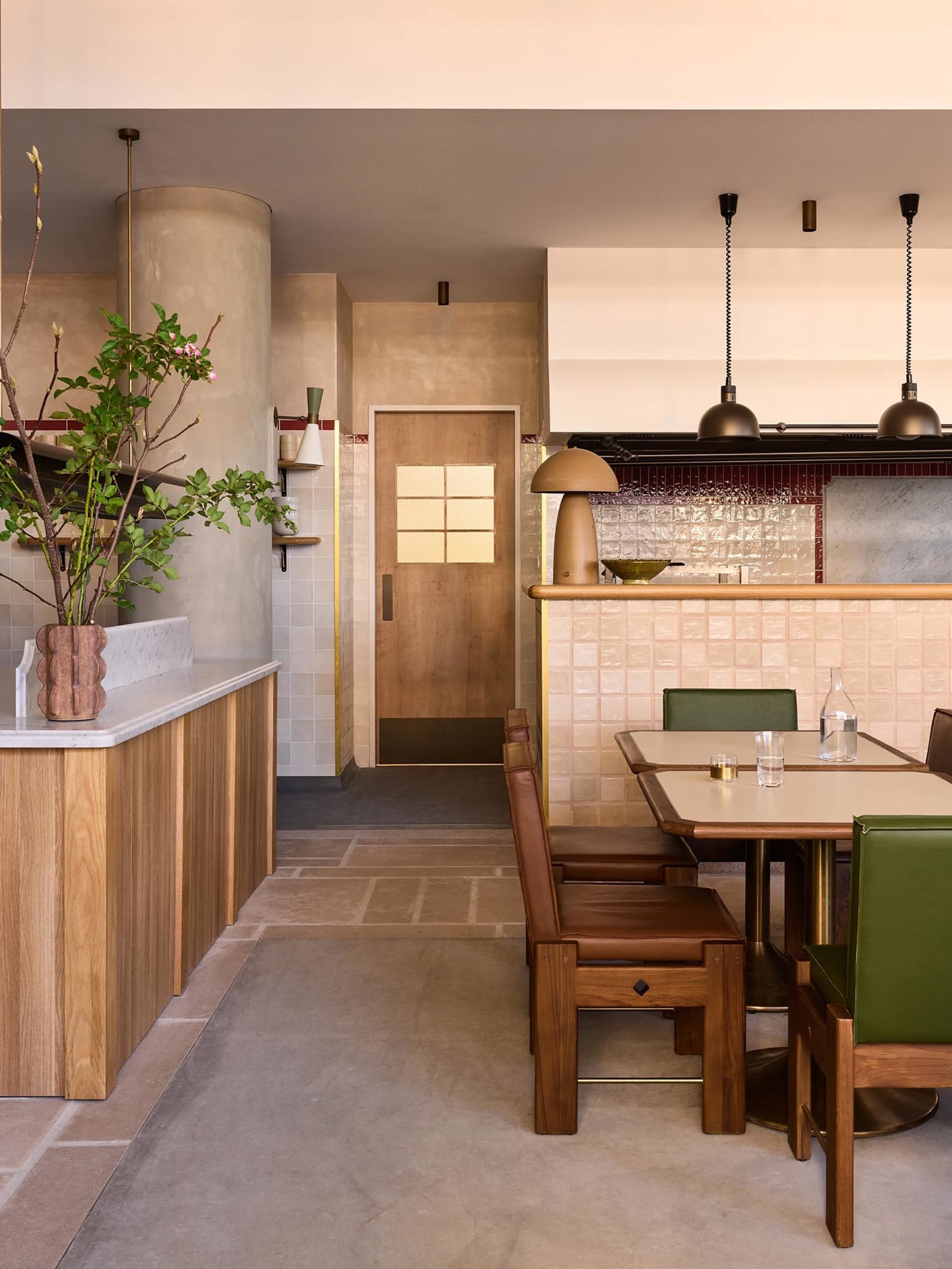 Interior of a rustic coffee shop featuring wooden furniture, a concrete counter, and ceramic tiles on the walls.
