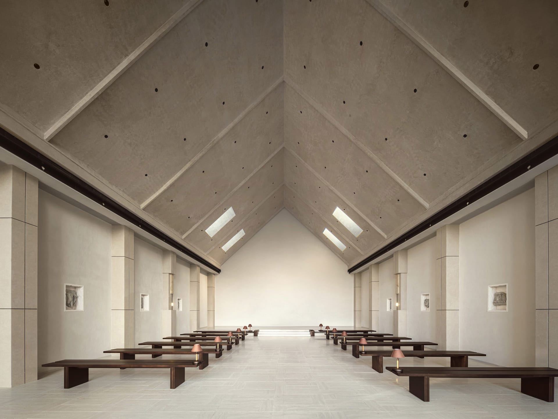 A minimalist, modern church interior with concrete walls and floors, high ceiling, and natural light.