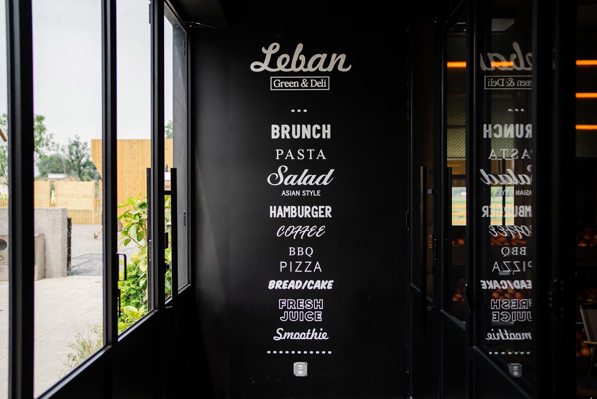 A black menu board featuring a list of food items in white text, including brunch, pasta, salad, hamburger, coffee, BBQ, pizz
