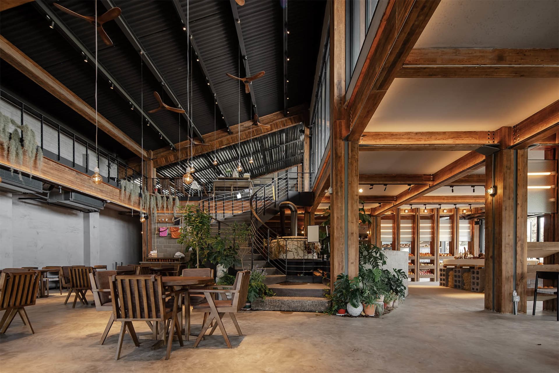 Industrial-style coffee shop interior with wood tables, chairs, and concrete flooring.