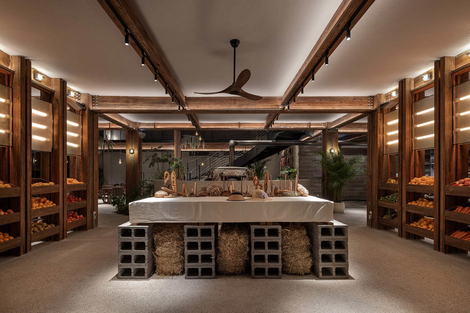 Industrial-style restaurant interior with wooden structures, concrete elements, and hay accents.