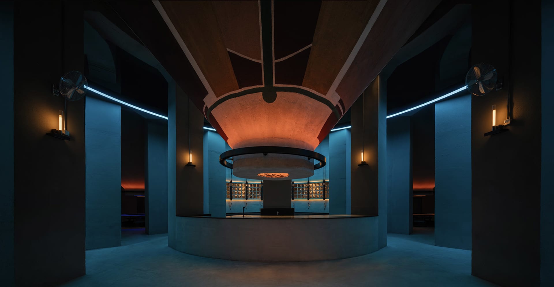 A modern, industrial-style lobby with concrete columns, arches, and flooring.