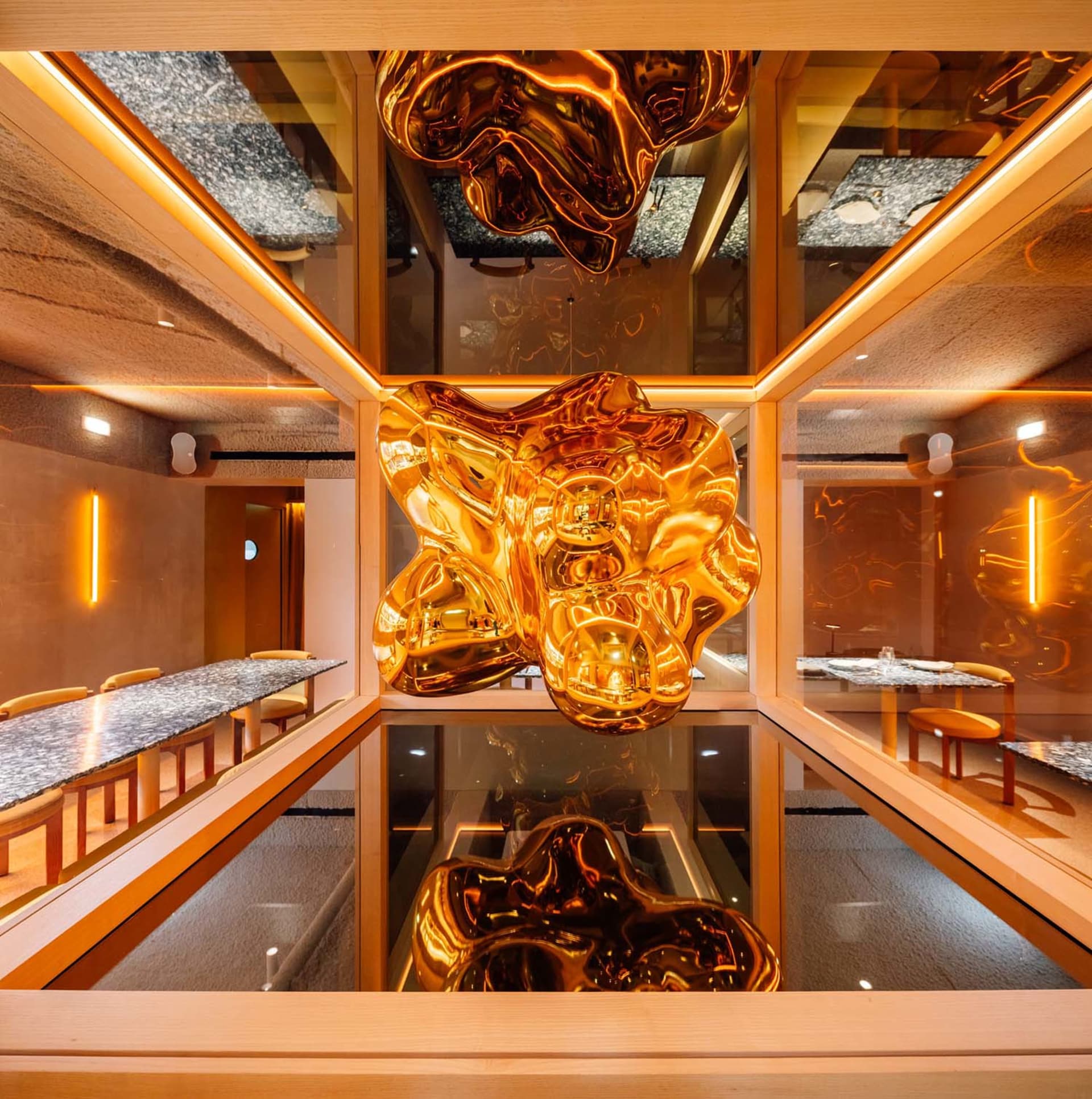 Modern restaurant interior featuring metallic sculptures hanging from the ceiling.