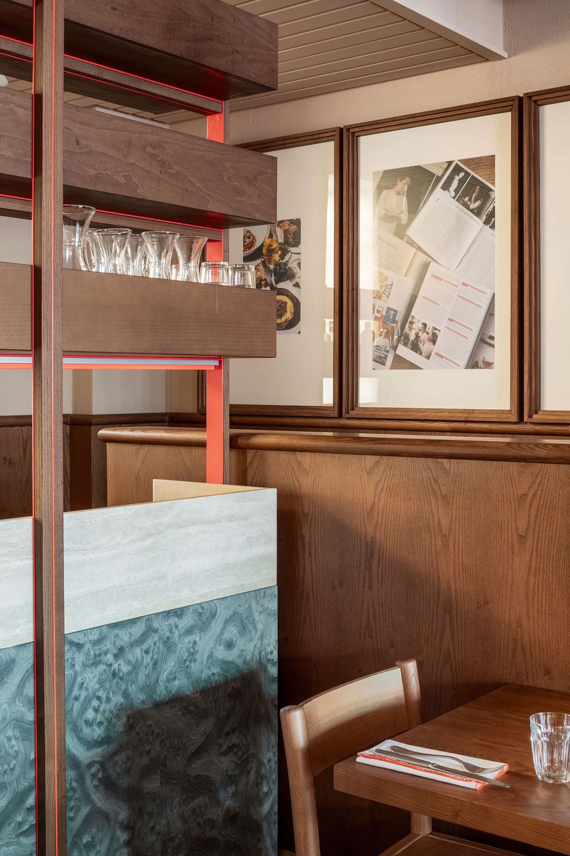 A modern restaurant booth with wooden seating and a marble divider.