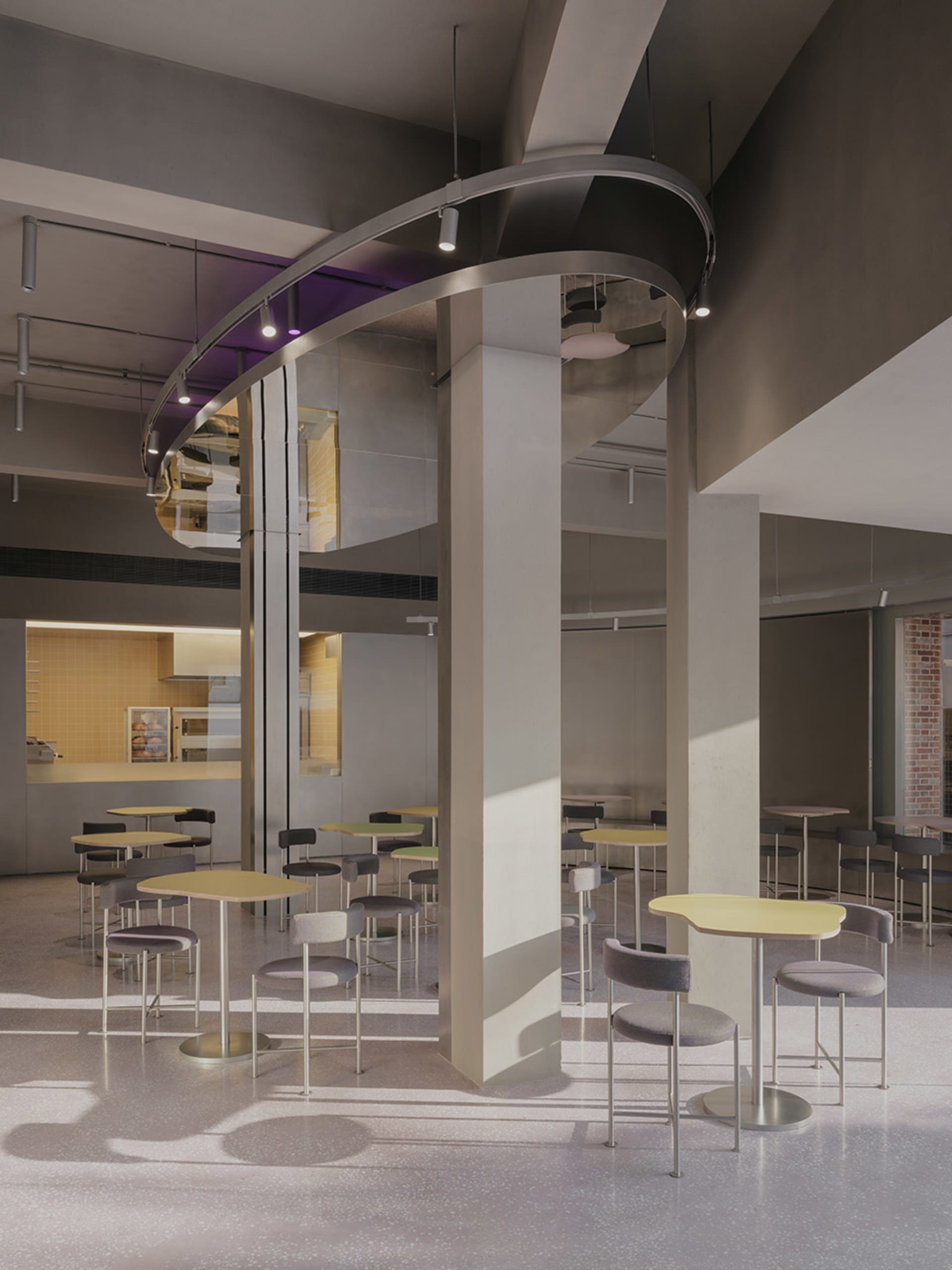 A spacious, industrial-style restaurant interior featuring concrete flooring, high ceilings, and modern lighting fixtures.