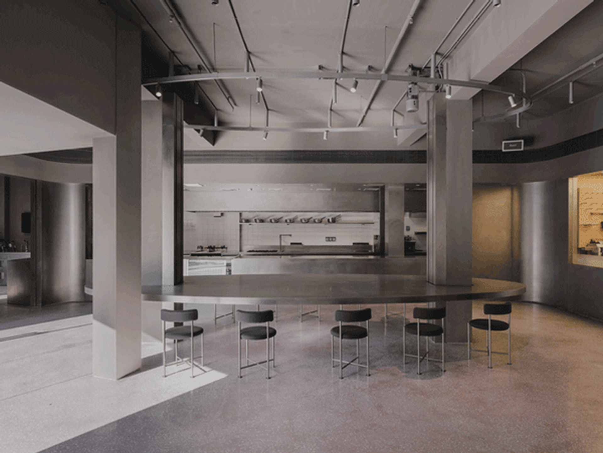 現代工業風餐廳室內,配有金屬餐桌、混凝土地板與玻璃隔板。