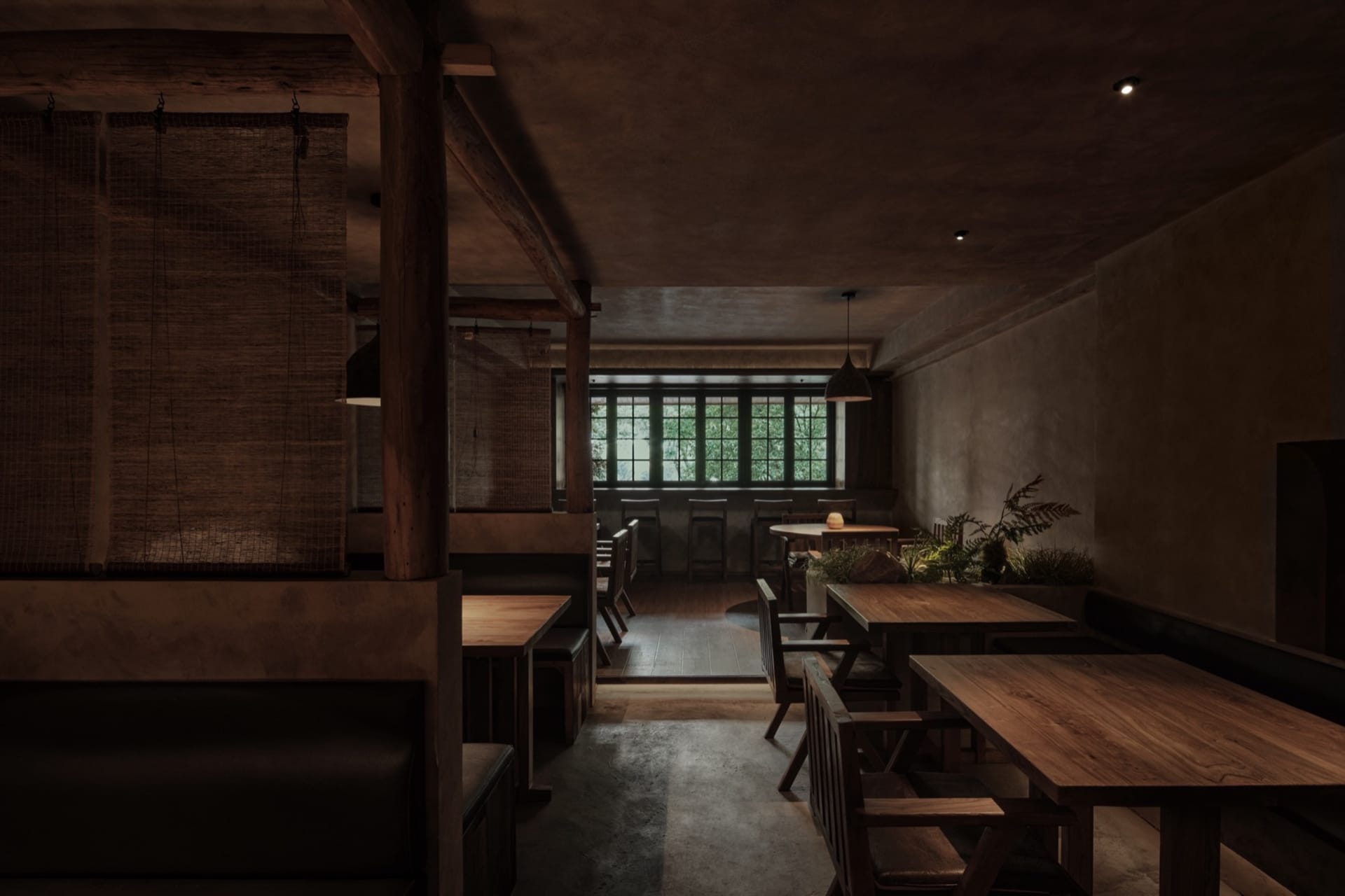 Interior of a restaurant featuring wooden tables, concrete flooring, and metallic accents.
