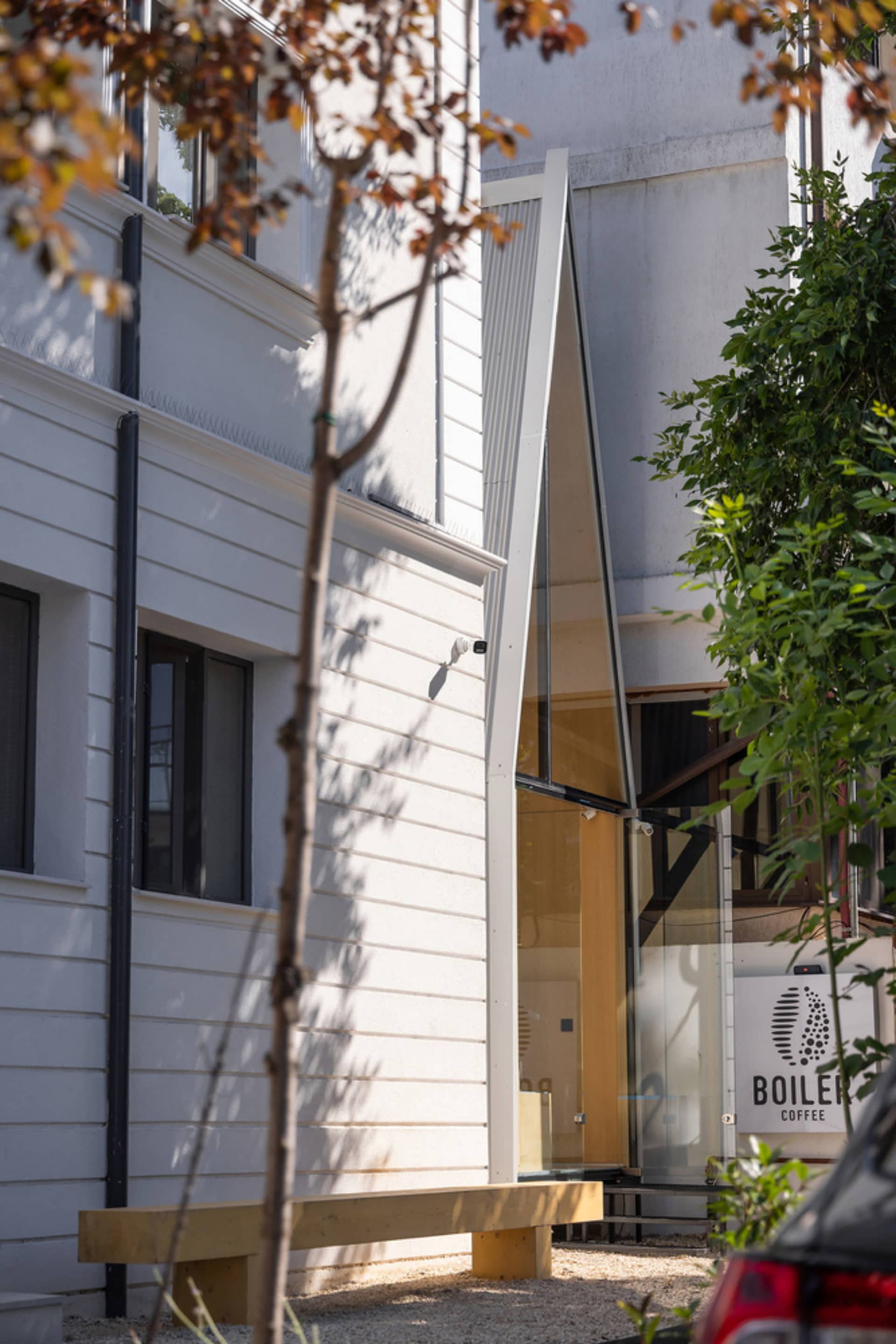 The exterior of a modern cafe featuring glass walls and wooden accents.